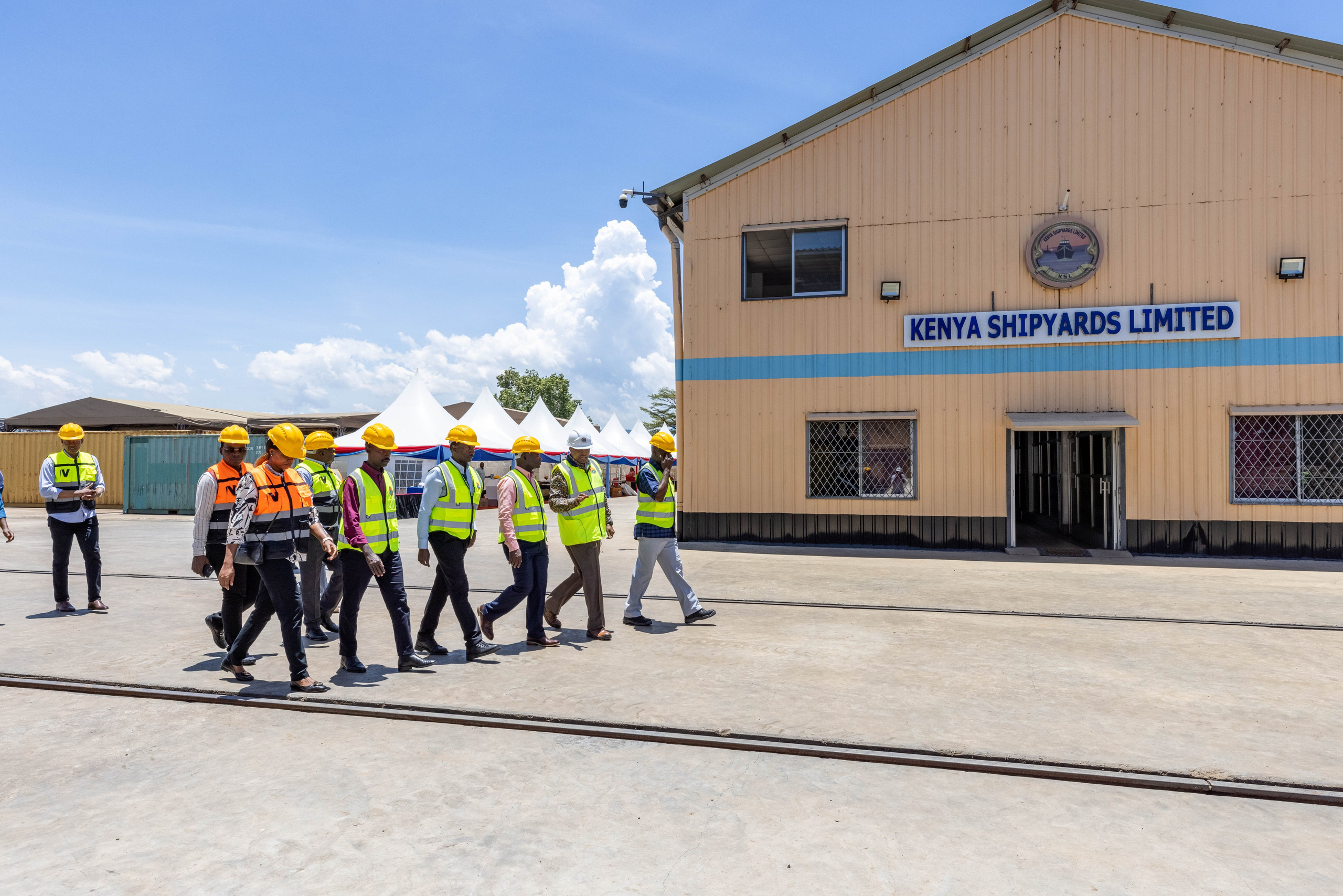 A wide angle photo of a group of visitors touring Kenya shipyards Kisumu office. Documentary photography