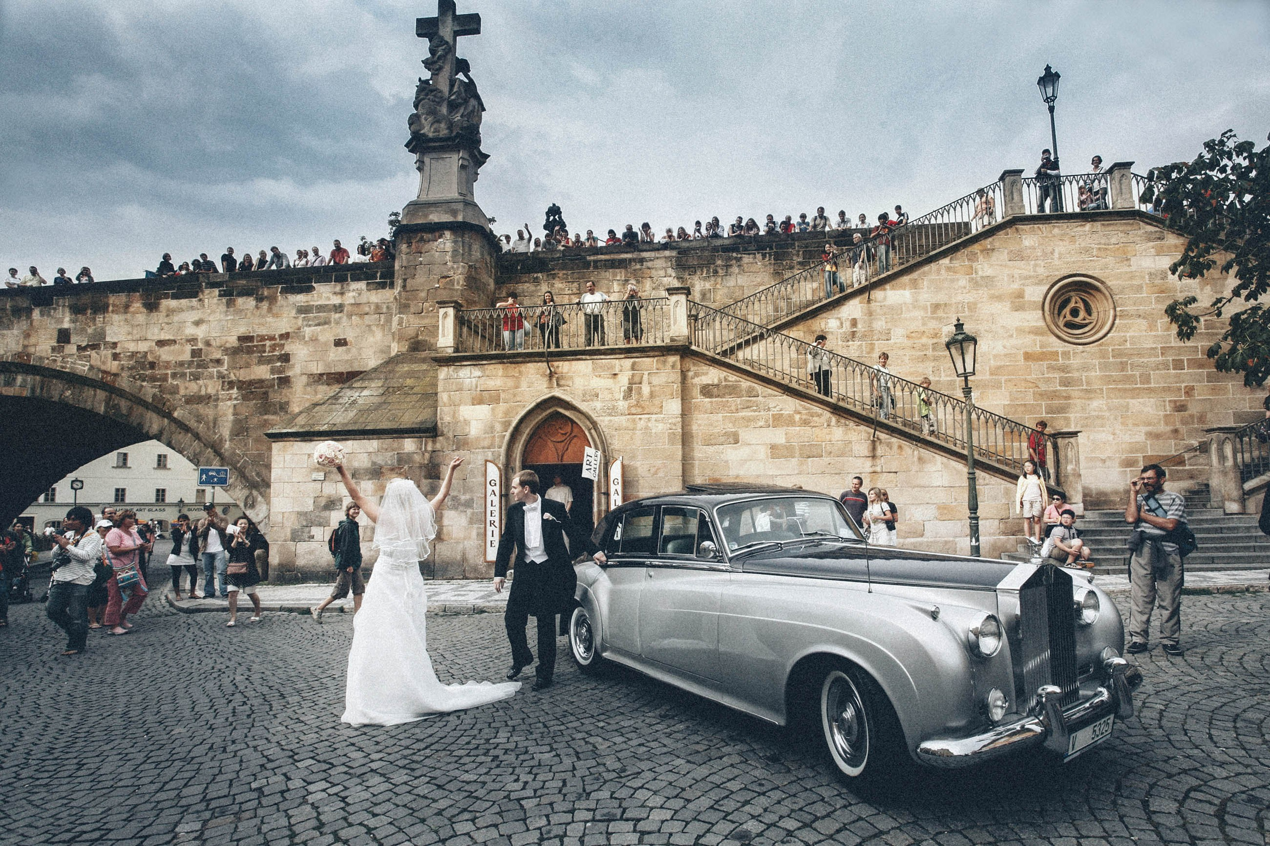 The newlyweds from Holland wave to the crowd of onlookers who applaud their arrival atop the Charles Bridge after exiting their Rolls Royce in Prague. 