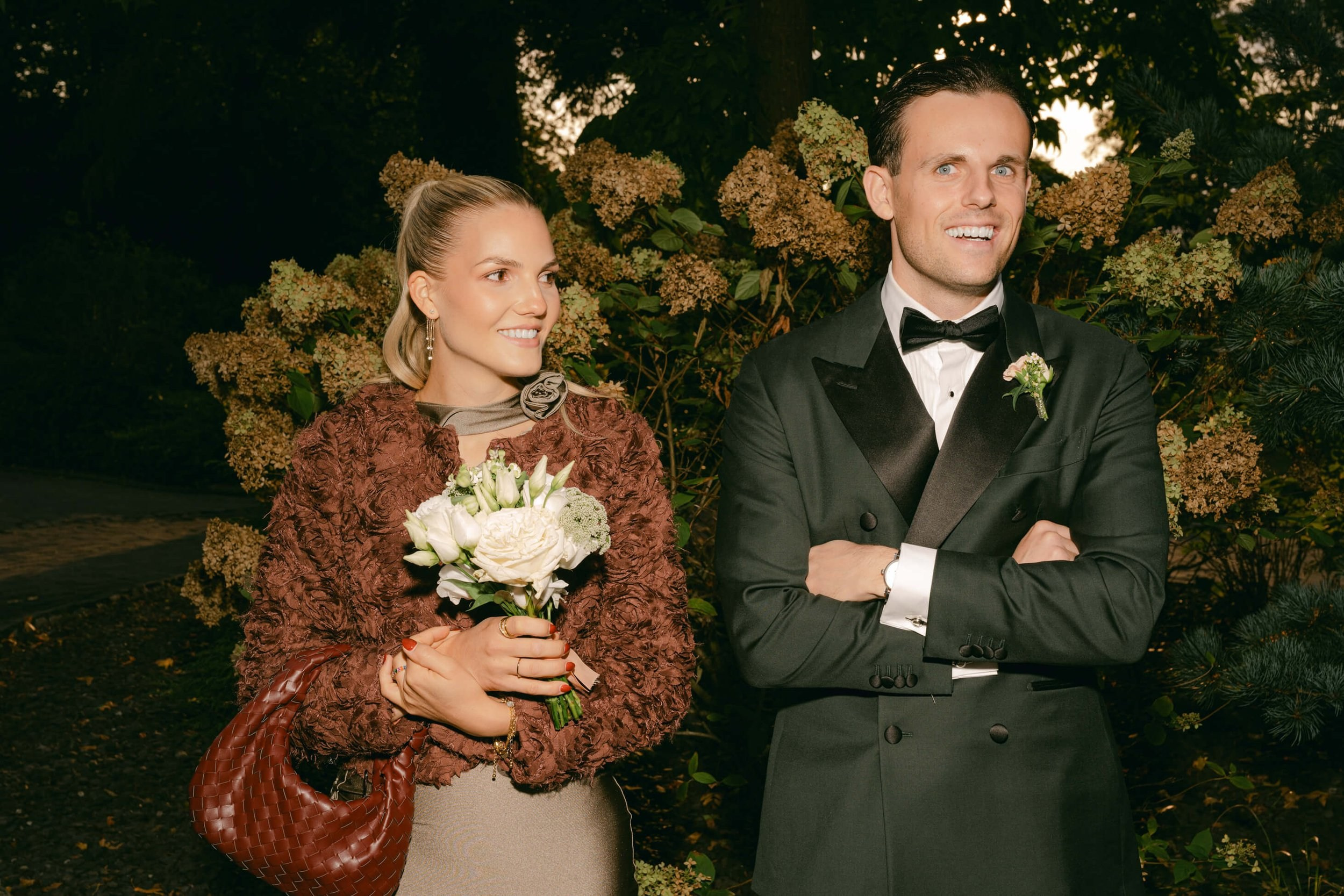 Groom in black tuxedo with wedding guest holding autumn flowers, black tie wedding Villa Rothschild Frankfurt
