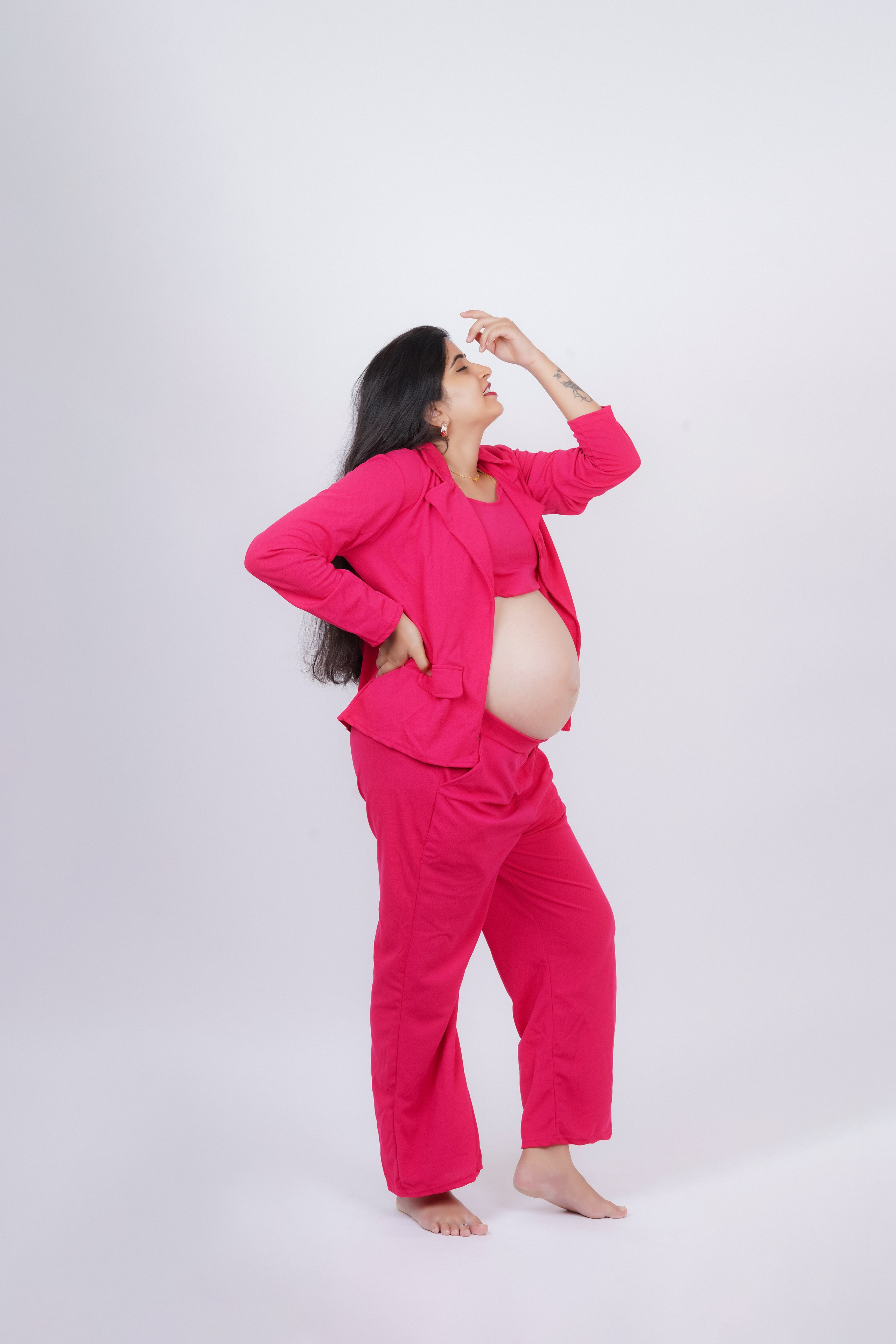 professional studio portrait of a pregnant woman wearing a hot pink blazer and pants maternity outfit posing for a photoshoot in Malleshwaram, Bengaluru
