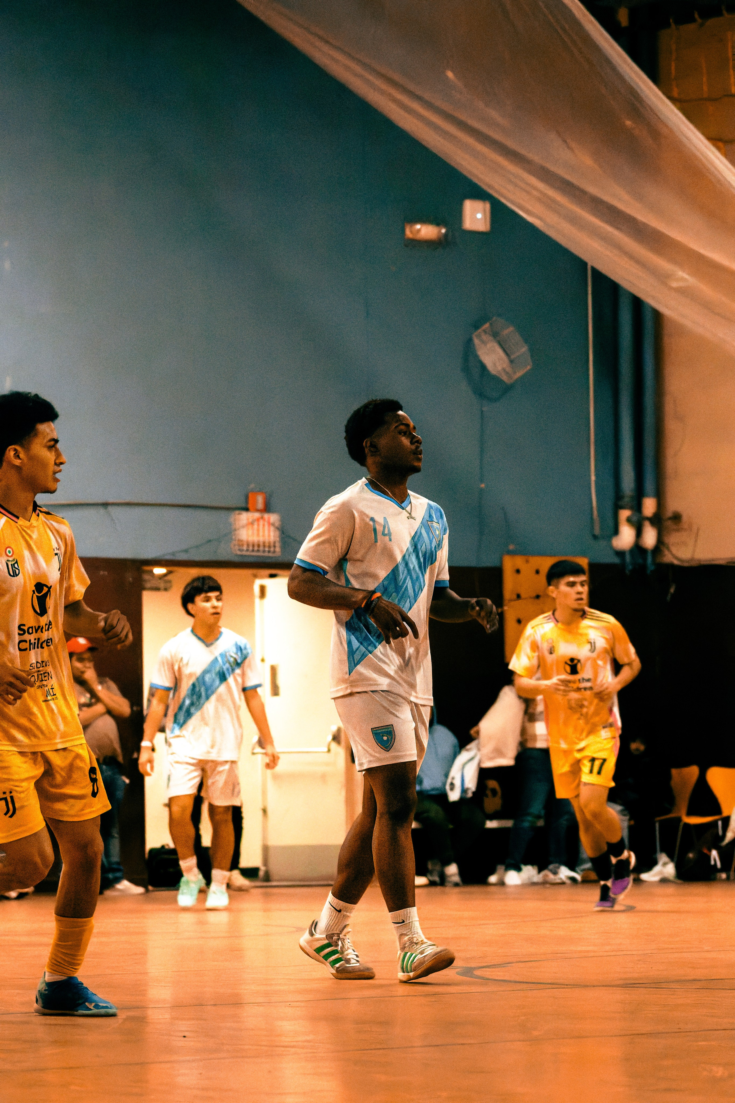 An indoor soccer player is jogging under the gym lights during a live play near the goal.