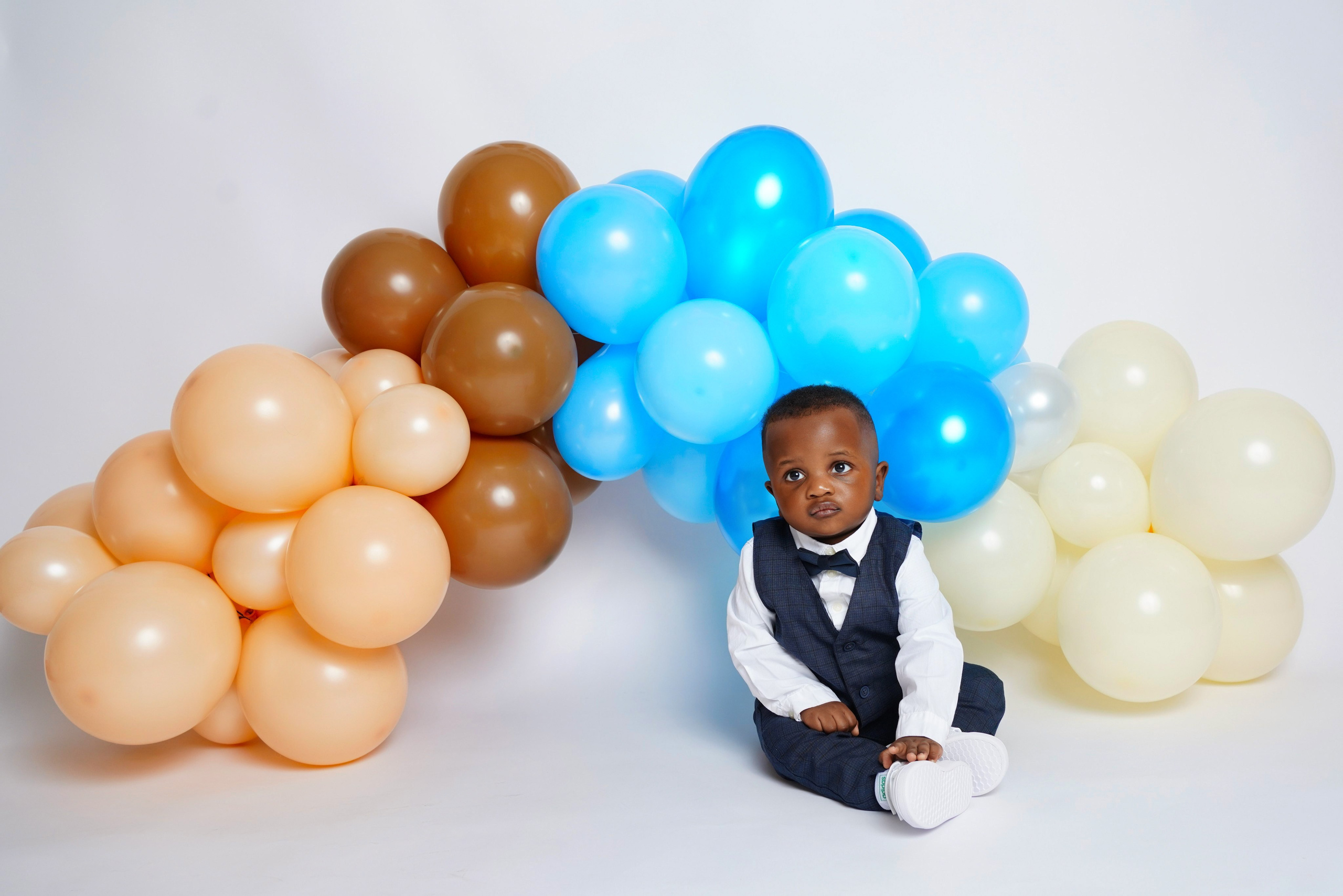 Eleganter Junge im Hemd mit Fliege vor einer bunten Ballongirlande – Fotostudio Augsburg