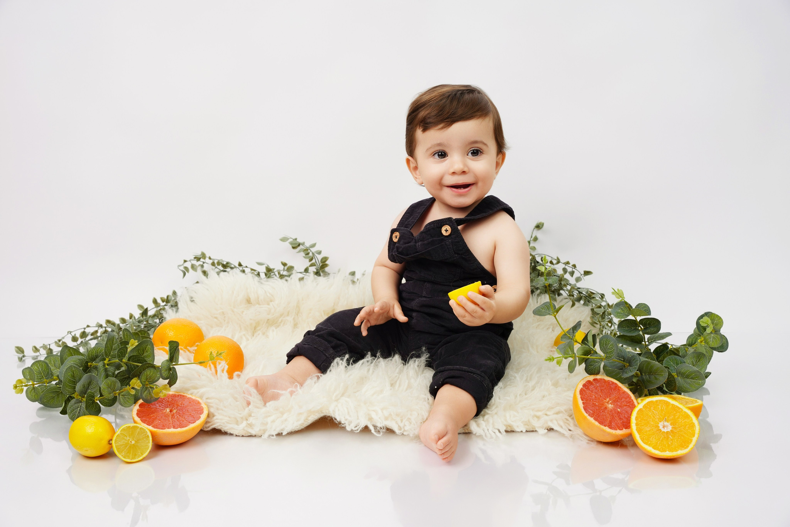 Fröhliches Baby-Fotoshooting auf hellem Fell mit frischen Orangen und Grapefruits – Augsburg