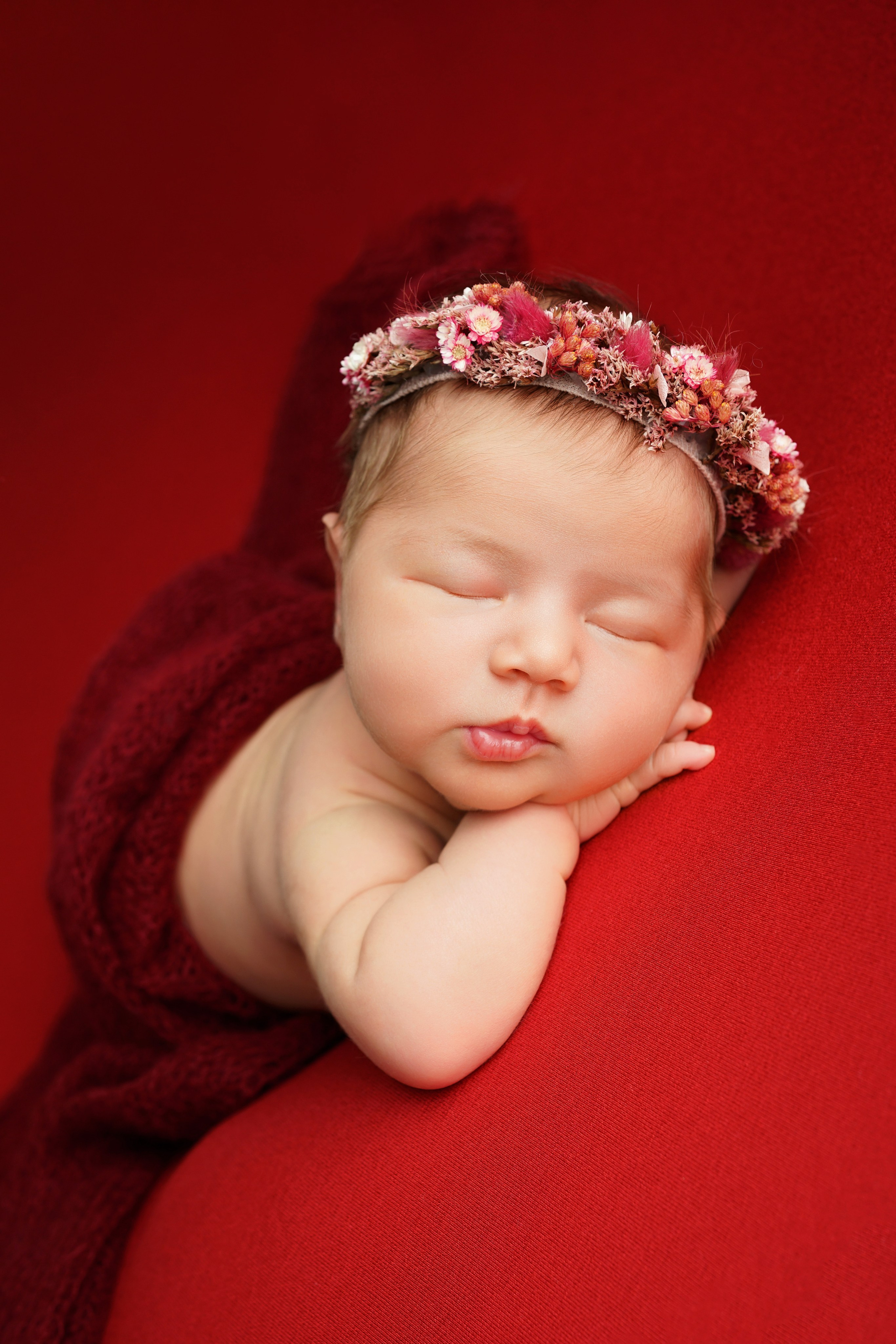Schlafendes Baby Kinn-auf-Händen-Pose auf rotem Hintergrund – Fotostudio in Augsburg