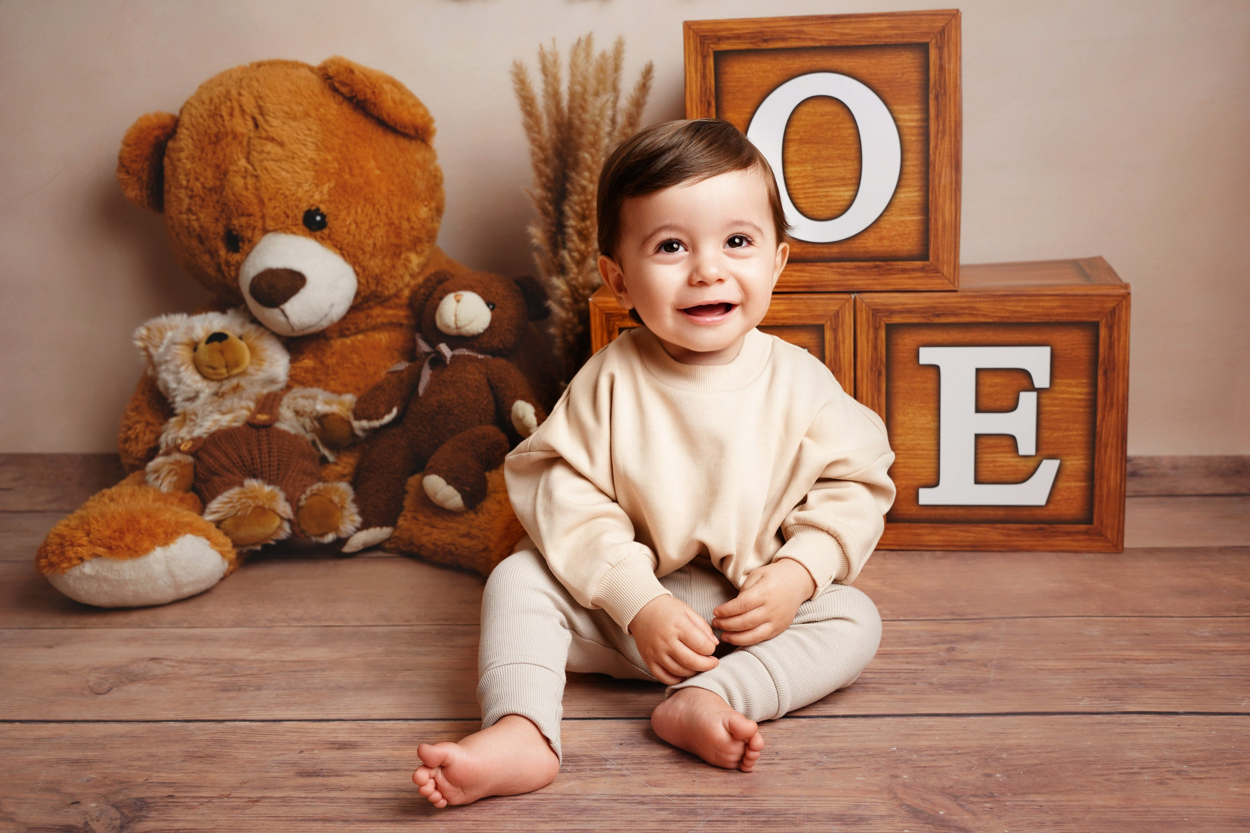 Kleinkind sitzt auf Holzfußboden neben ONE-Holzwürfeln und großem Teddybär – Kinderfotograf Augsburg