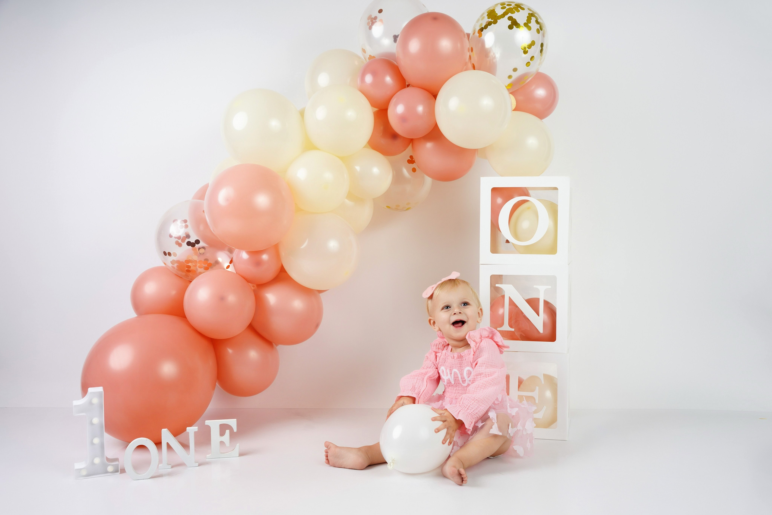Erster Geburtstag von kleinem Mädchen mit pastellfarbenem Ballonbogen – Cake Smash Fotograf Augsburg