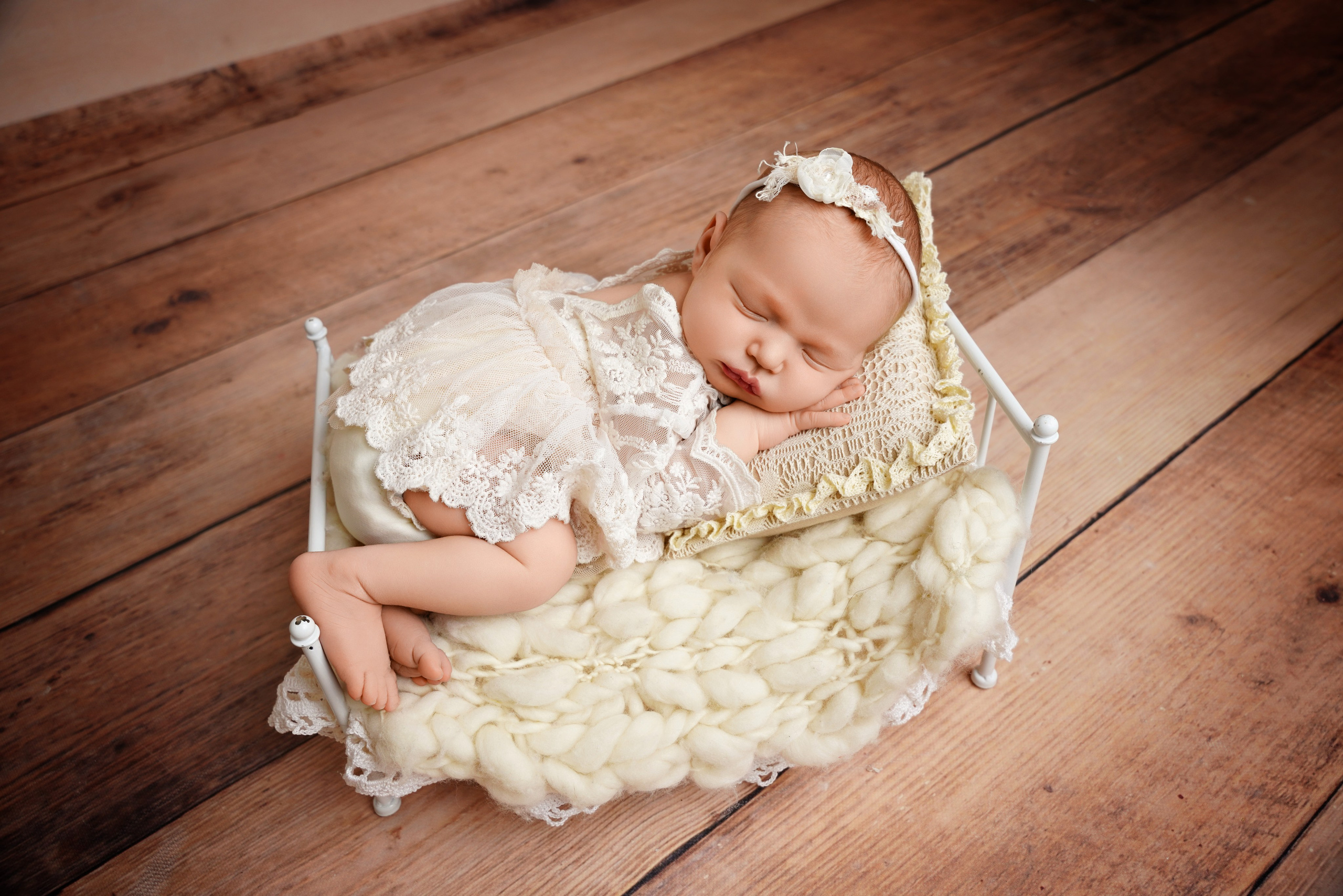 Süßes Neugeborenes schlafend auf einem Mini-Vintage-Bettchen im Fotostudio Augsburg
