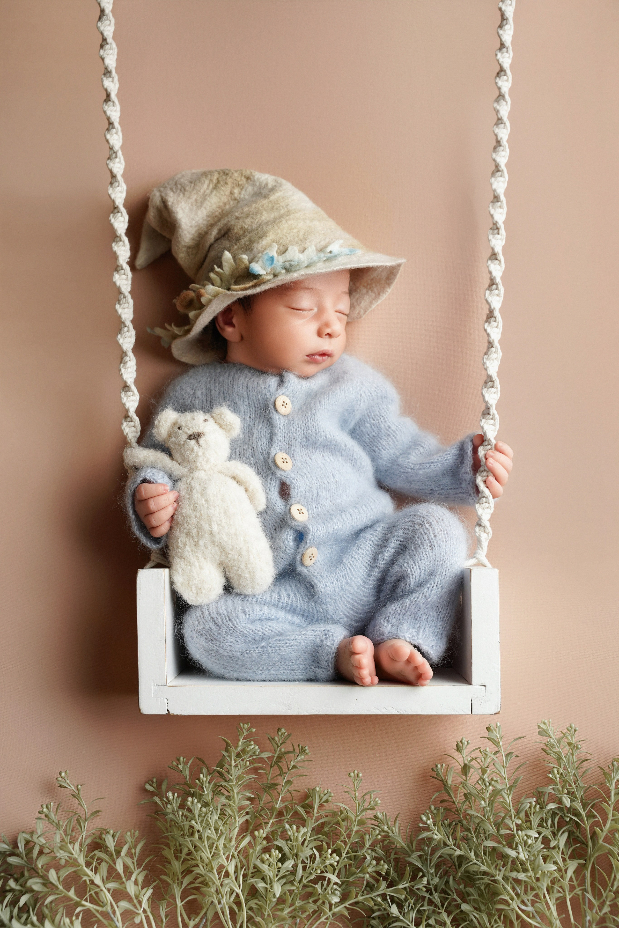 Schlafendes Baby auf der Schauckel mit zarter Mütze – Neugeborenenfotostudio Augsburg