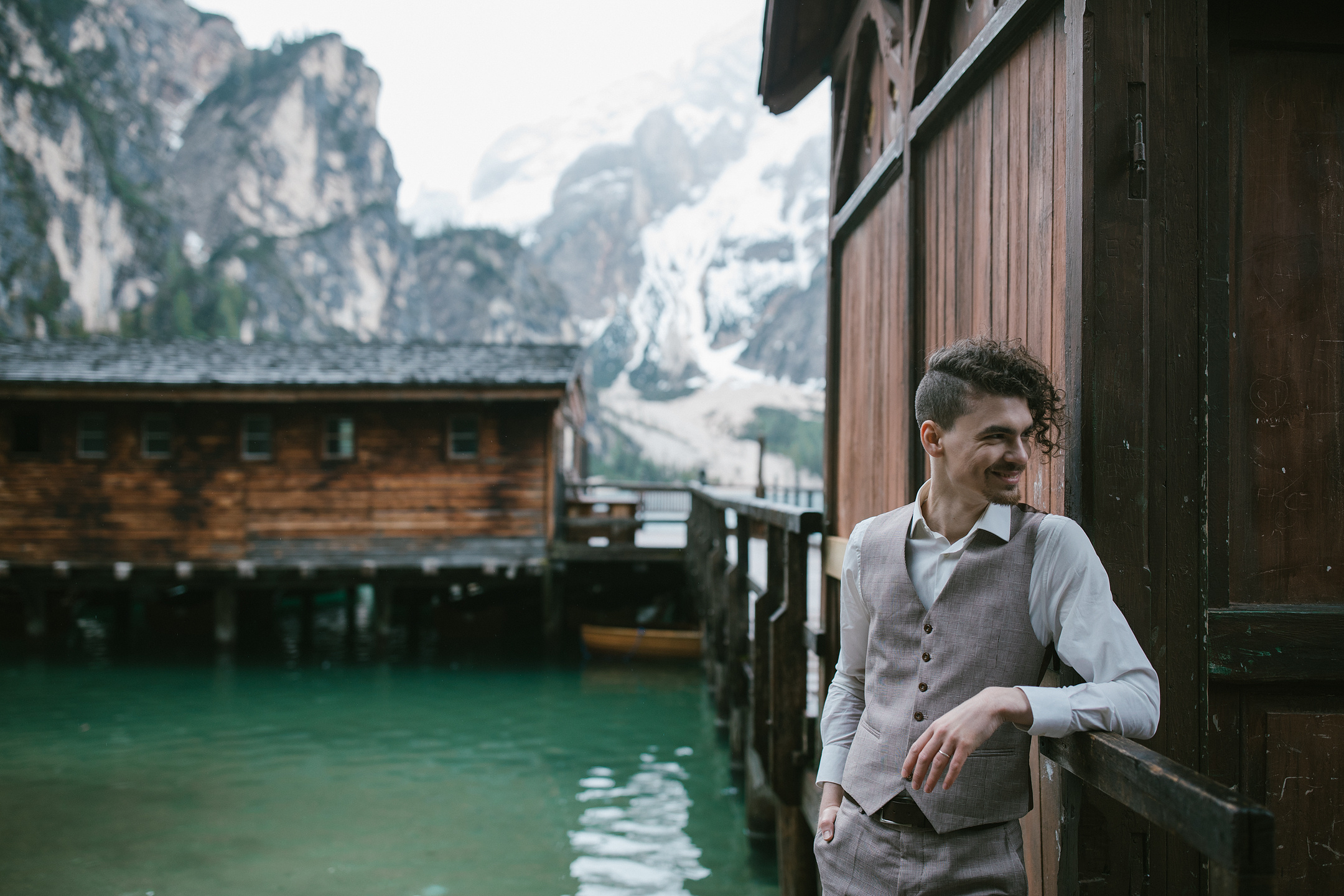 Bräutigam lächelt auf Holzsteg über Alpensee