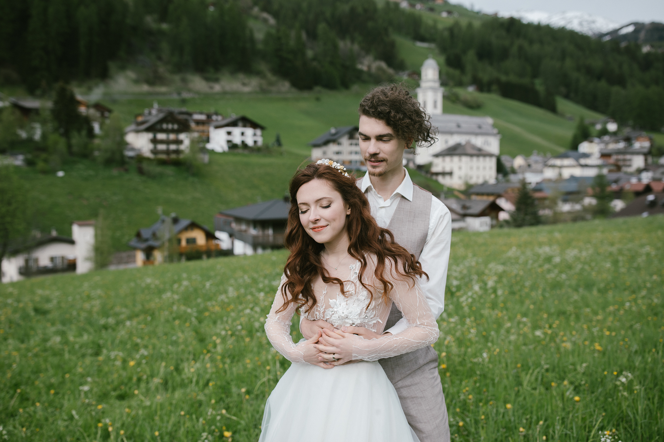 Bräutigam umarmt Braut in Dolomiten-Bergdorfwiese
