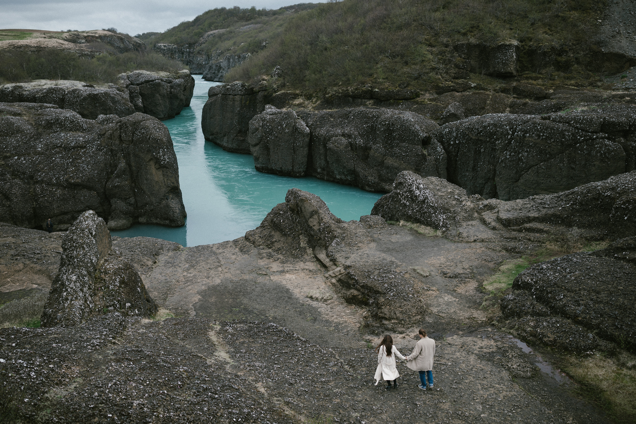 Hochzeitsfotografie Händchenhalten am Canyon mit türkisfarbenem Fluss