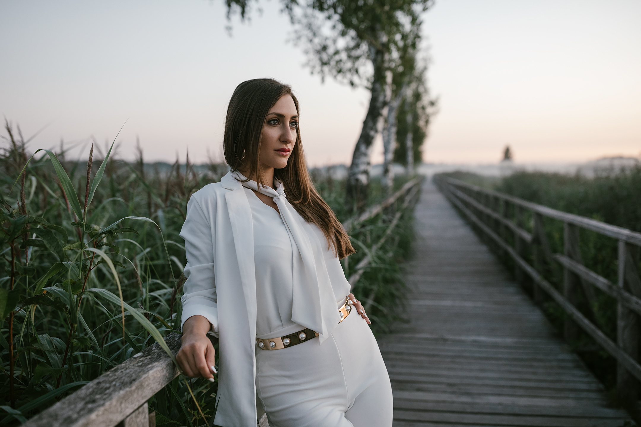 Morgenaufnahme einer Frau in Weiß auf Holzsteg am Federsee