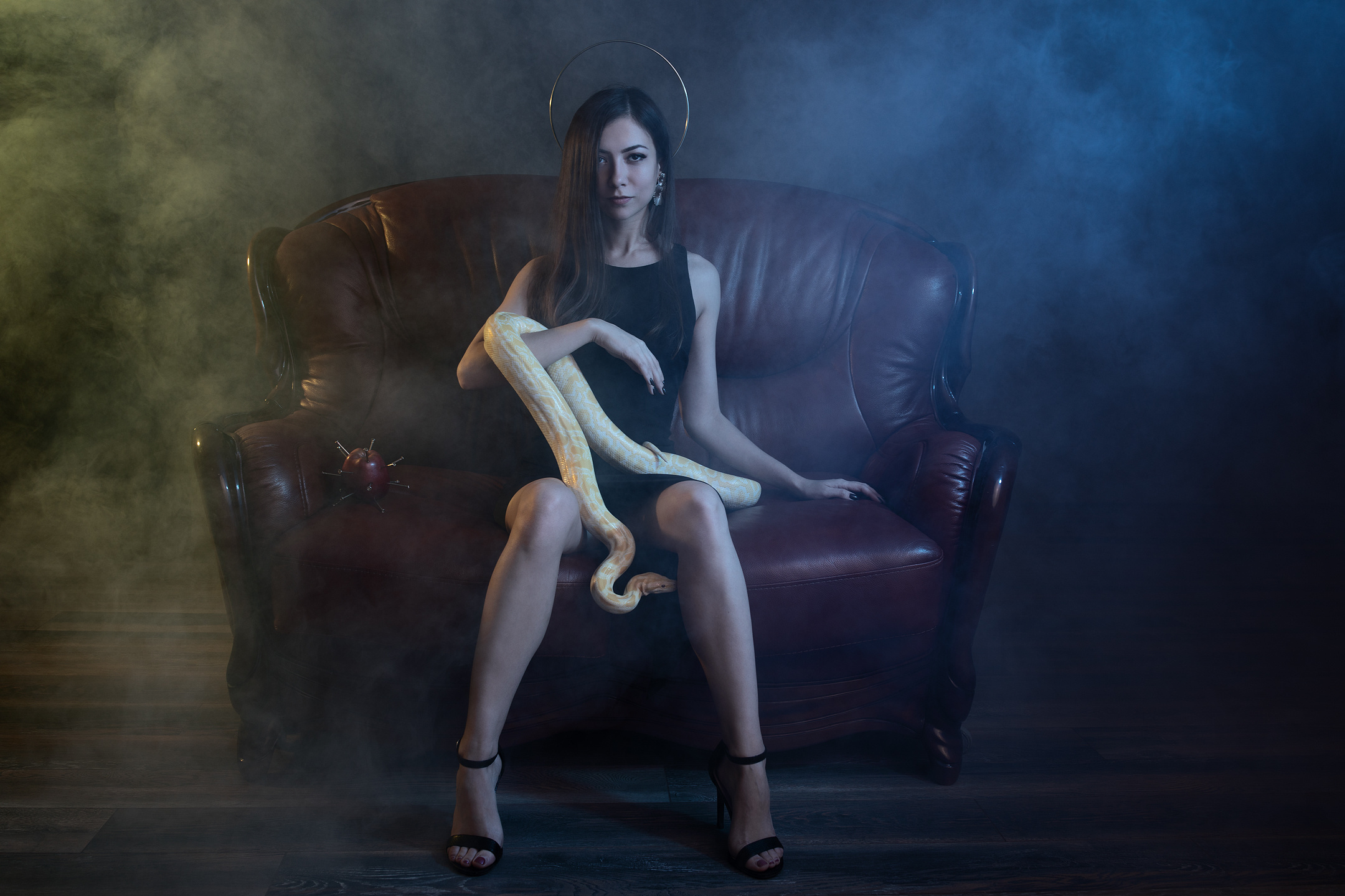 Fine art portrait of a woman with golden python on leather sofa, inspired by Eve