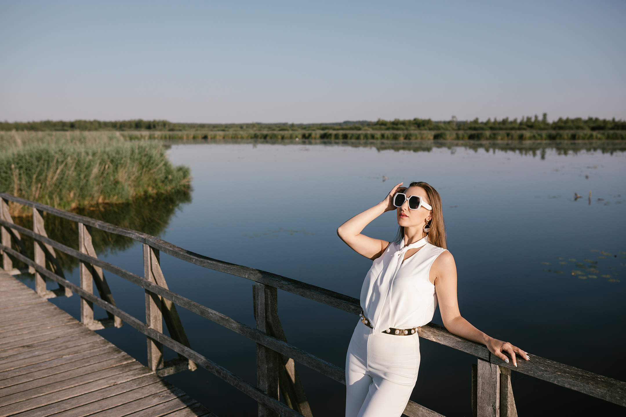 Porträtaufnahme im Sonnenaufgang auf Steg mit Blick über den See