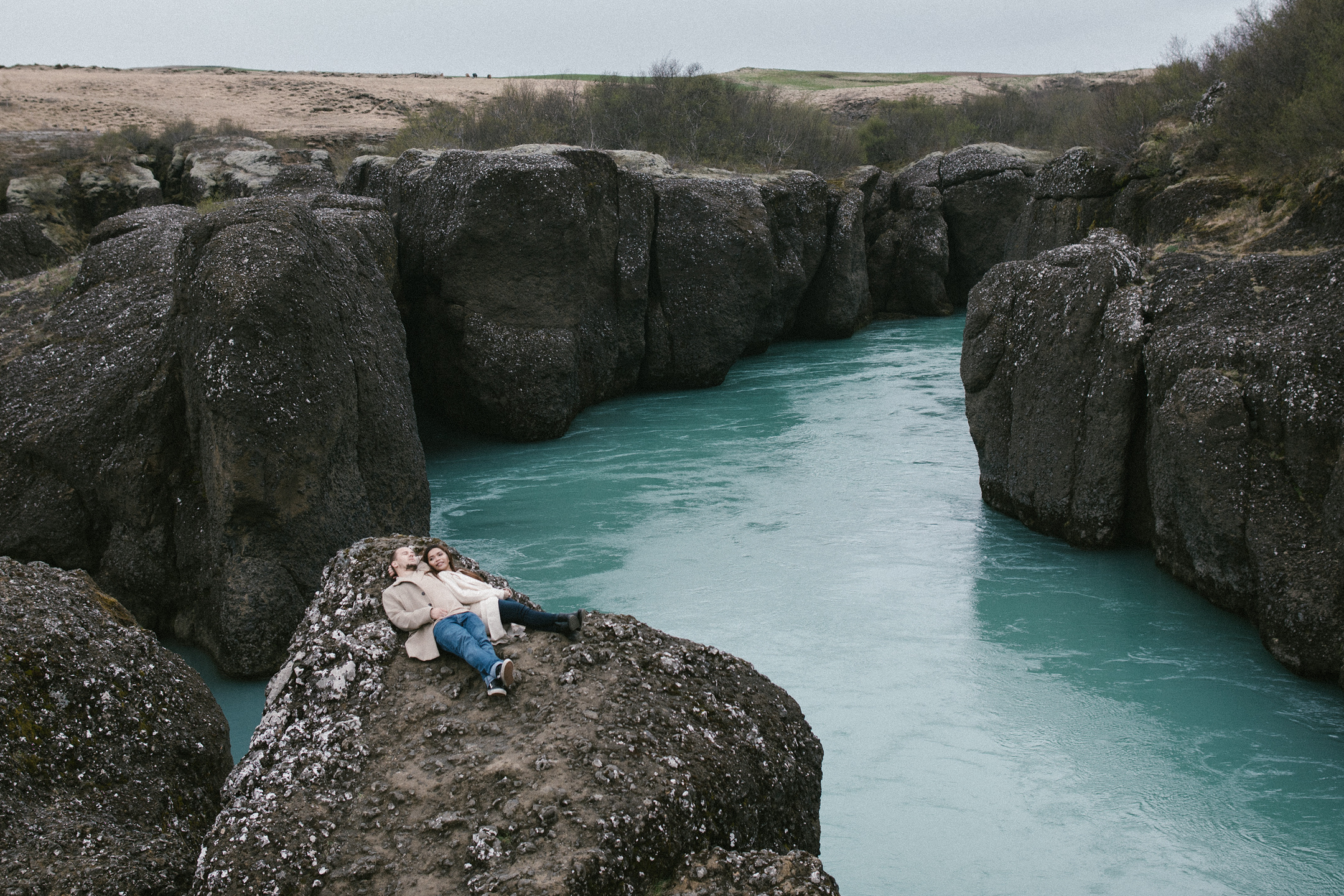 Paarshooting auf Felsen über türkisfarbenem Fluss in Island