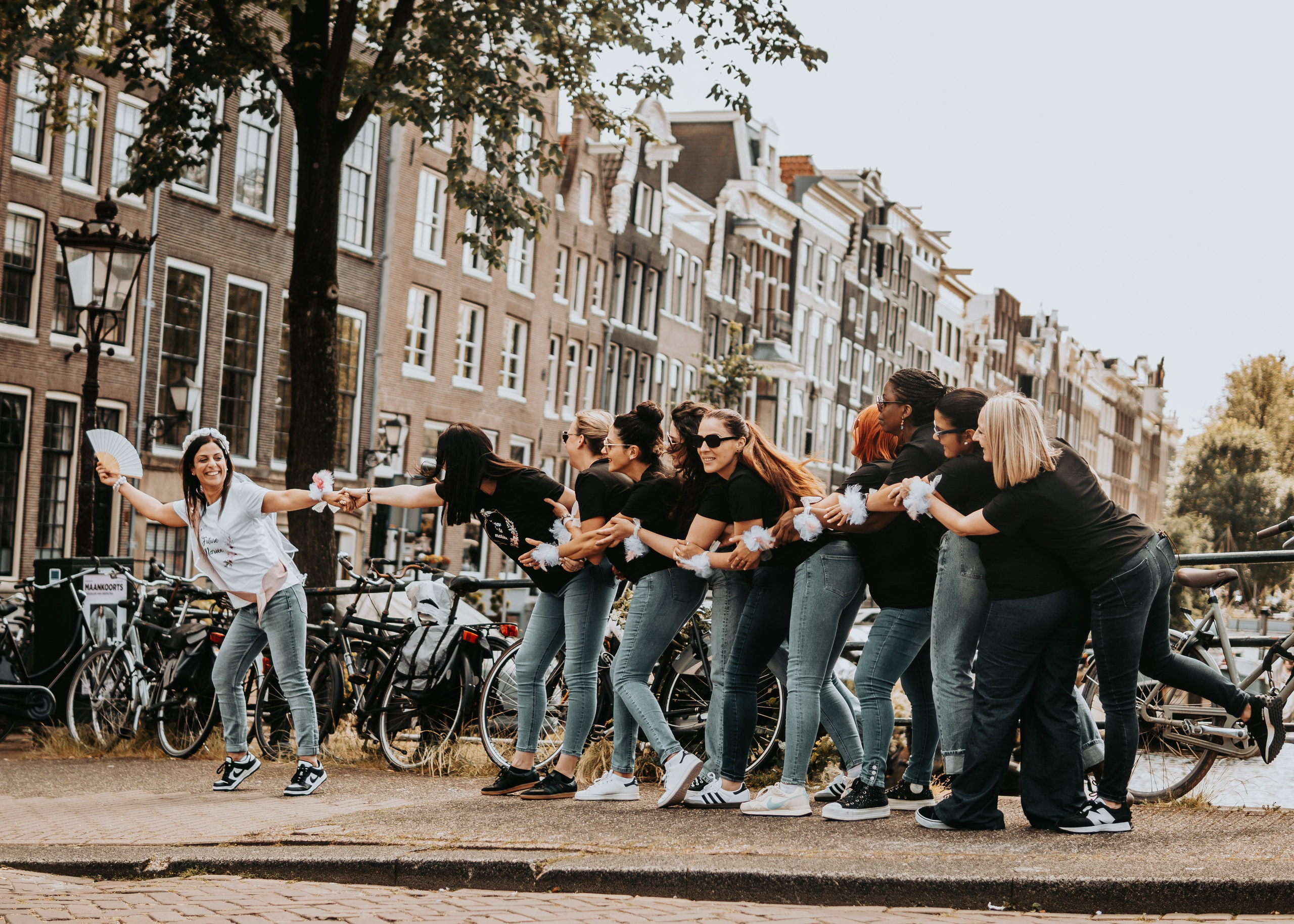 girls pulling the bride to be with canal houses view behind them