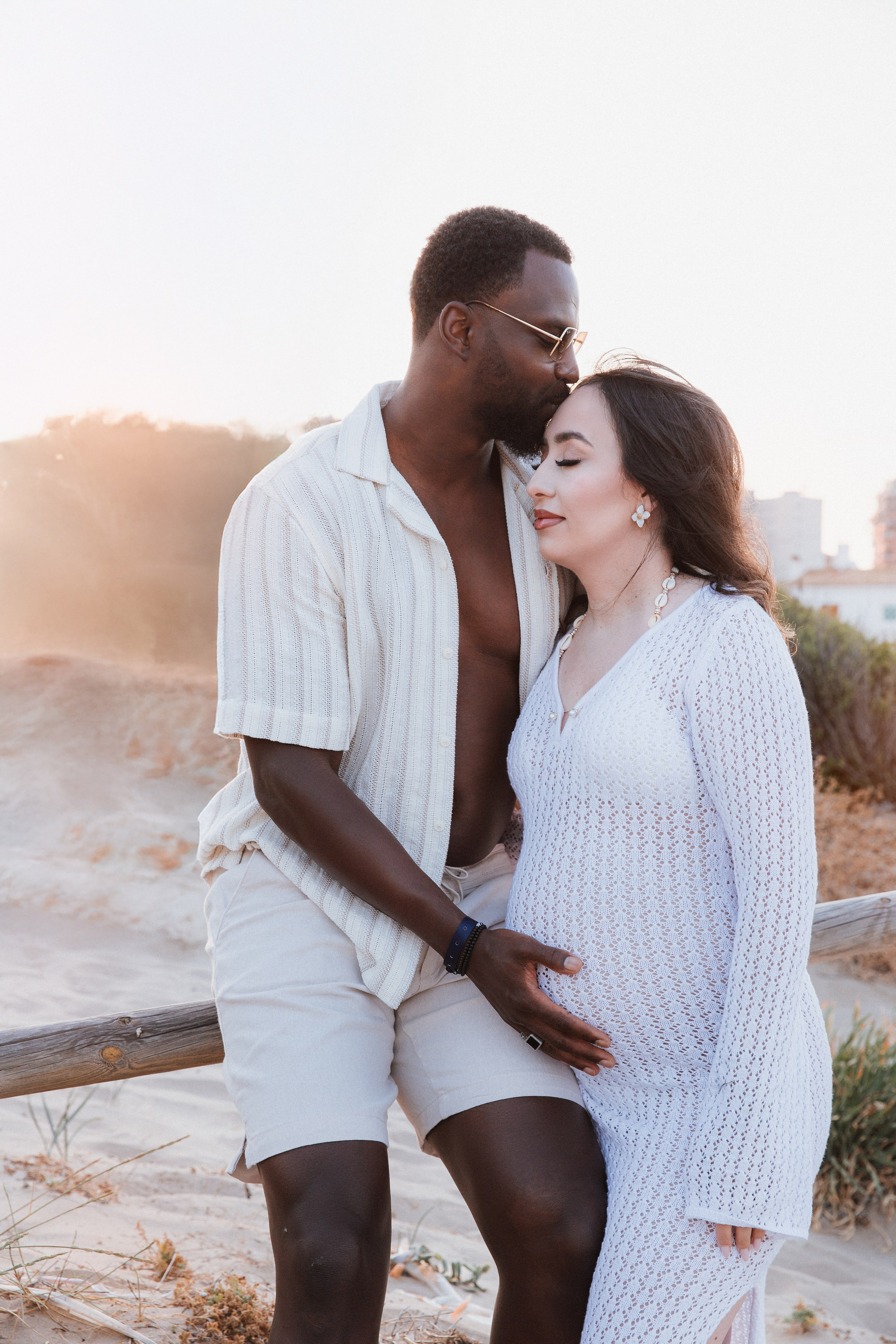 Sesión romántica de maternidad en Jávea, España — pareja compartiendo un momento tierno al atardecer mientras el padre acaricia la barriga. Ideal para quienes buscan fotos naturales y emocionales de embarazo en Jávea y la Costa Blanca.
