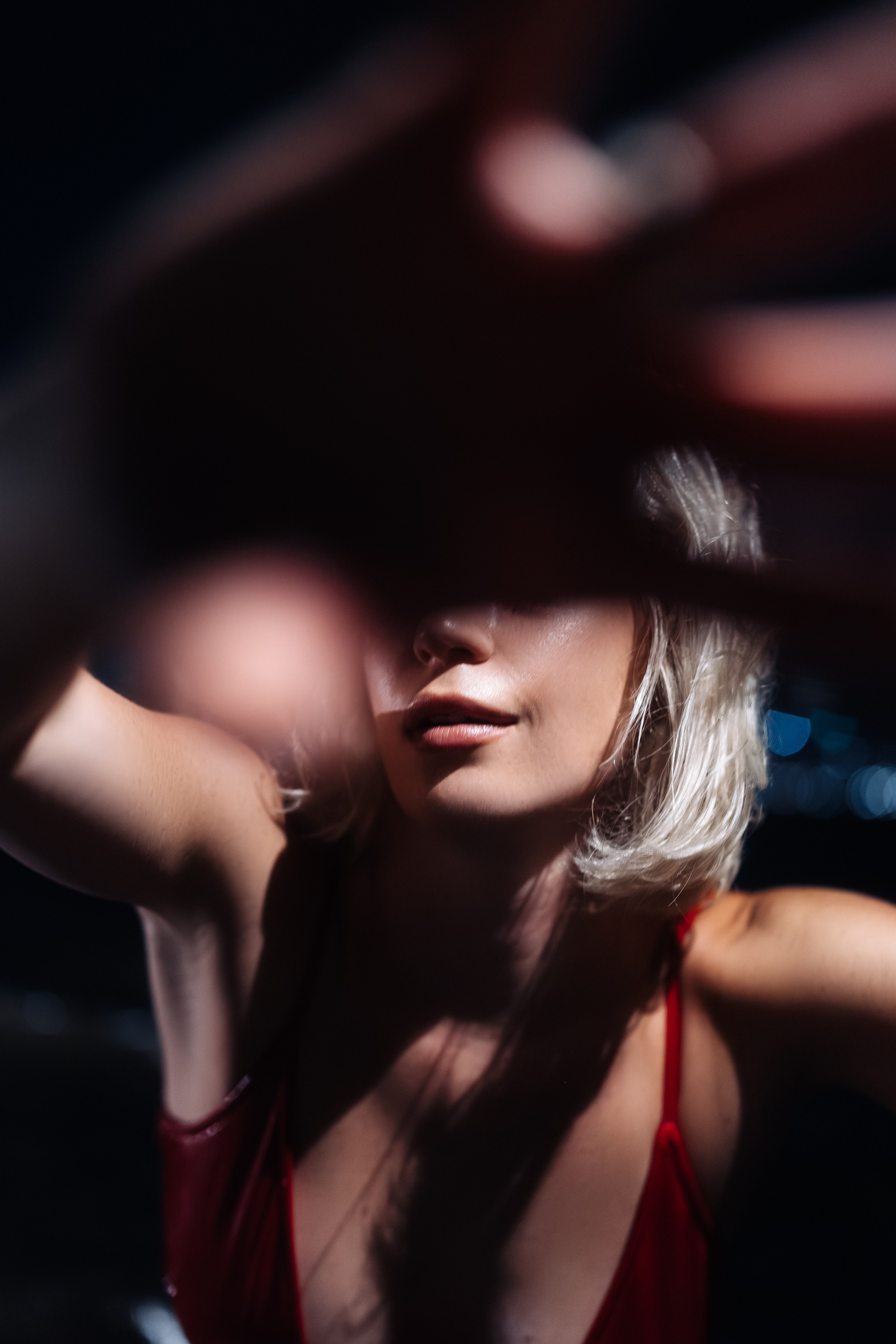 The model smiles softly as the wind touches her hair. A gentle, living moment in the night.