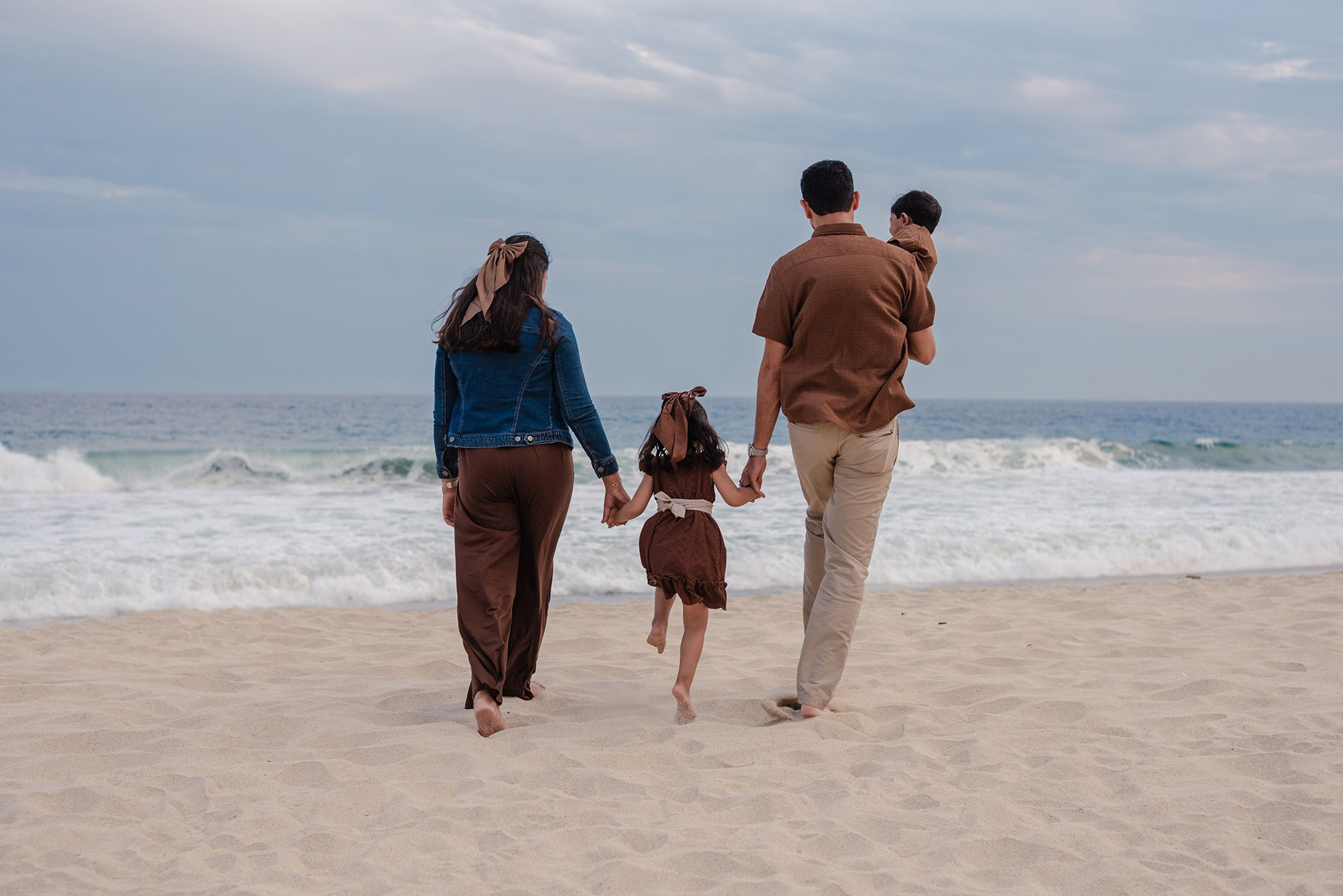 Family of four walking away along the shoreline at Hyatt Ziva Los Cabos