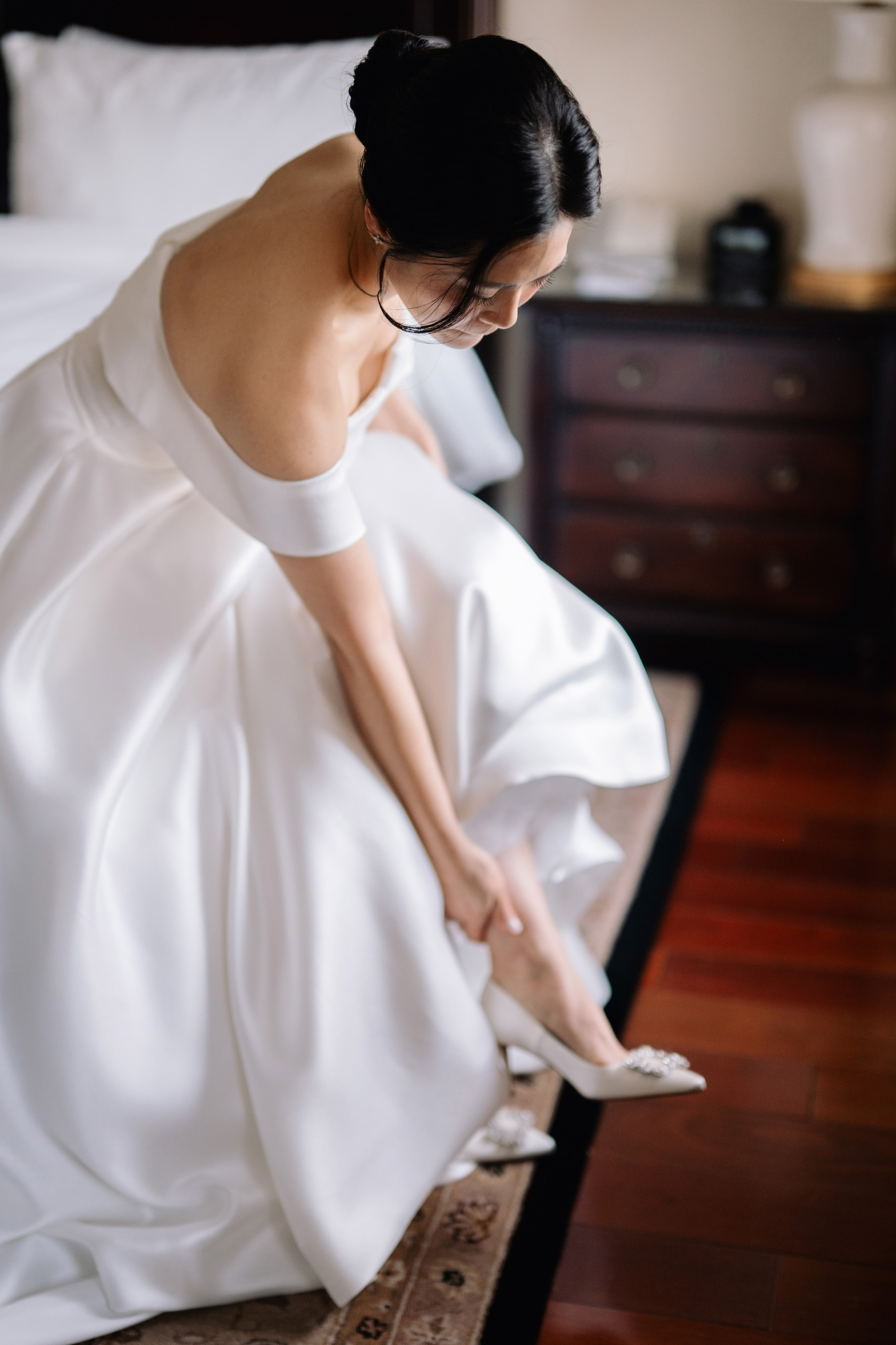 a woman in a white dress is putting on her shoes