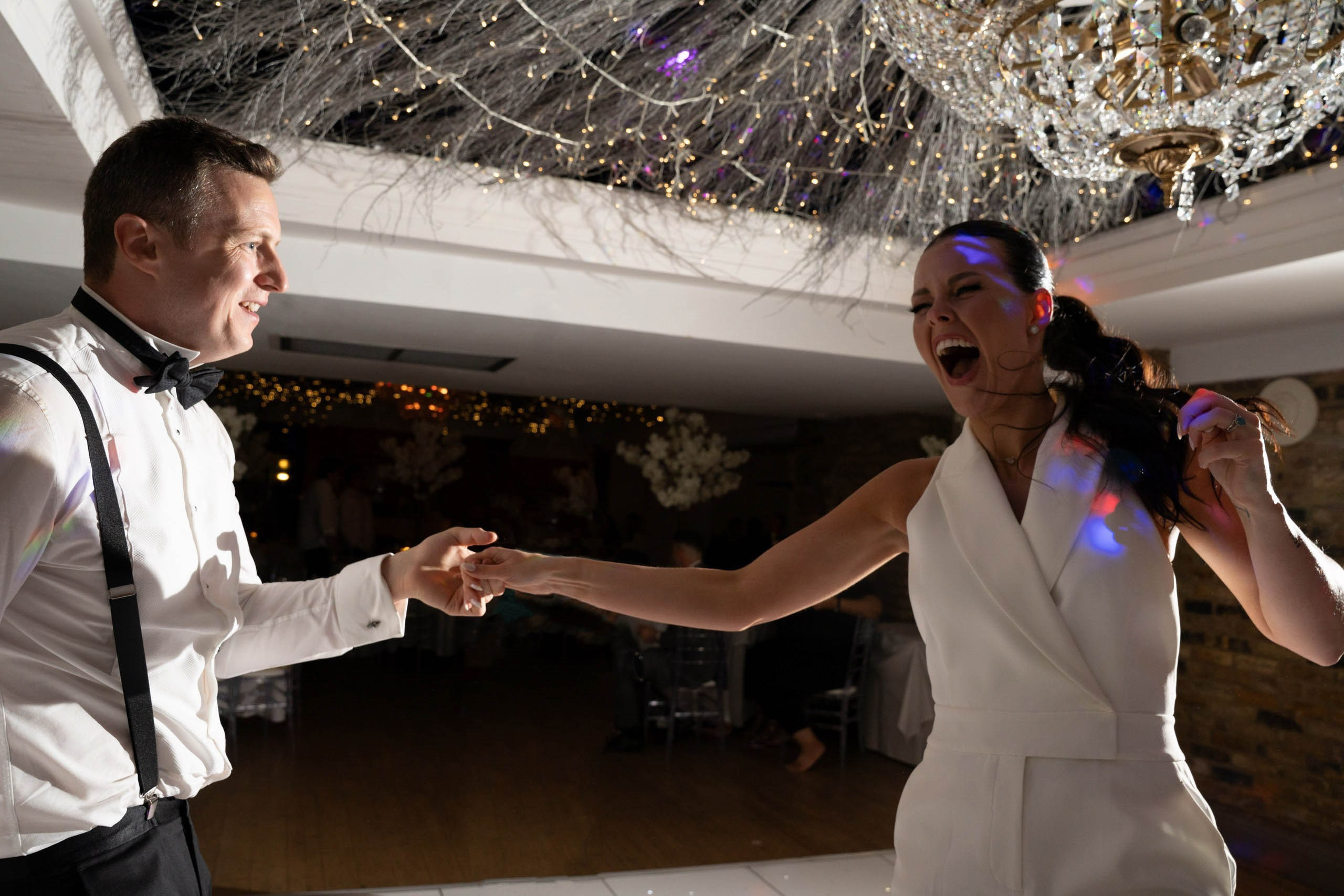 Groom and bride dancing with guests watching, lively UK wedding reception, documentary style capturing authentic emotions