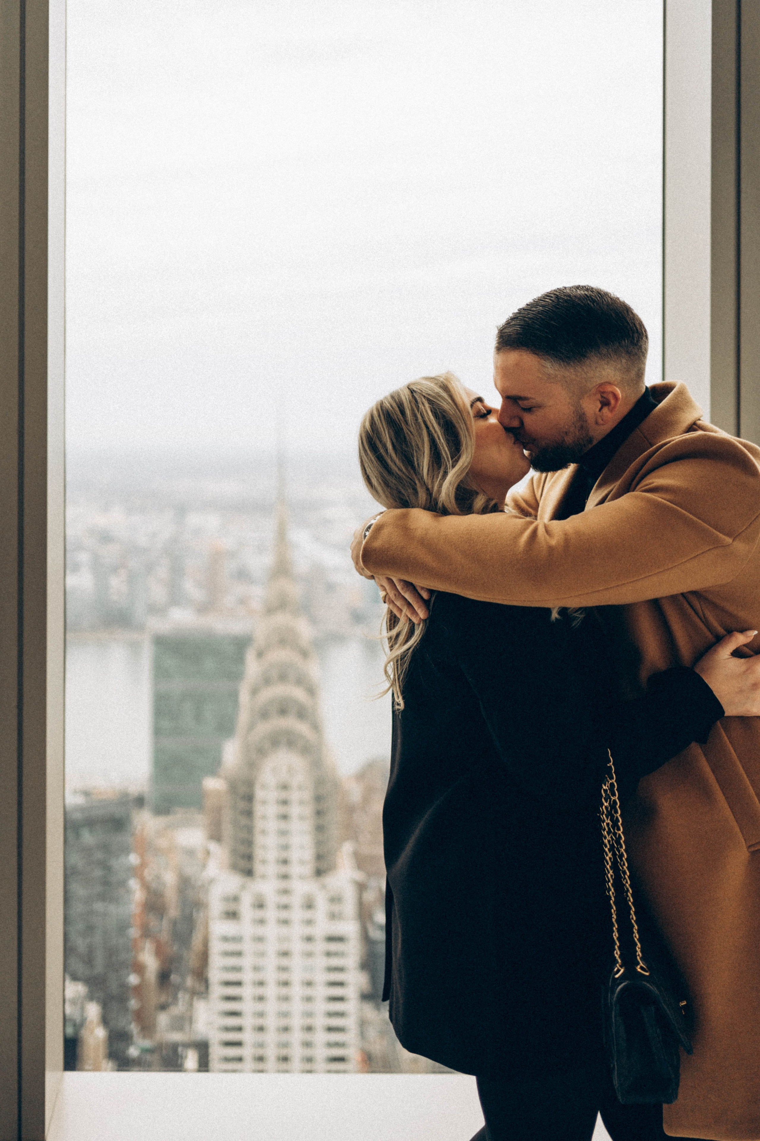 Couple laughing in Dumbo after engagement moment.