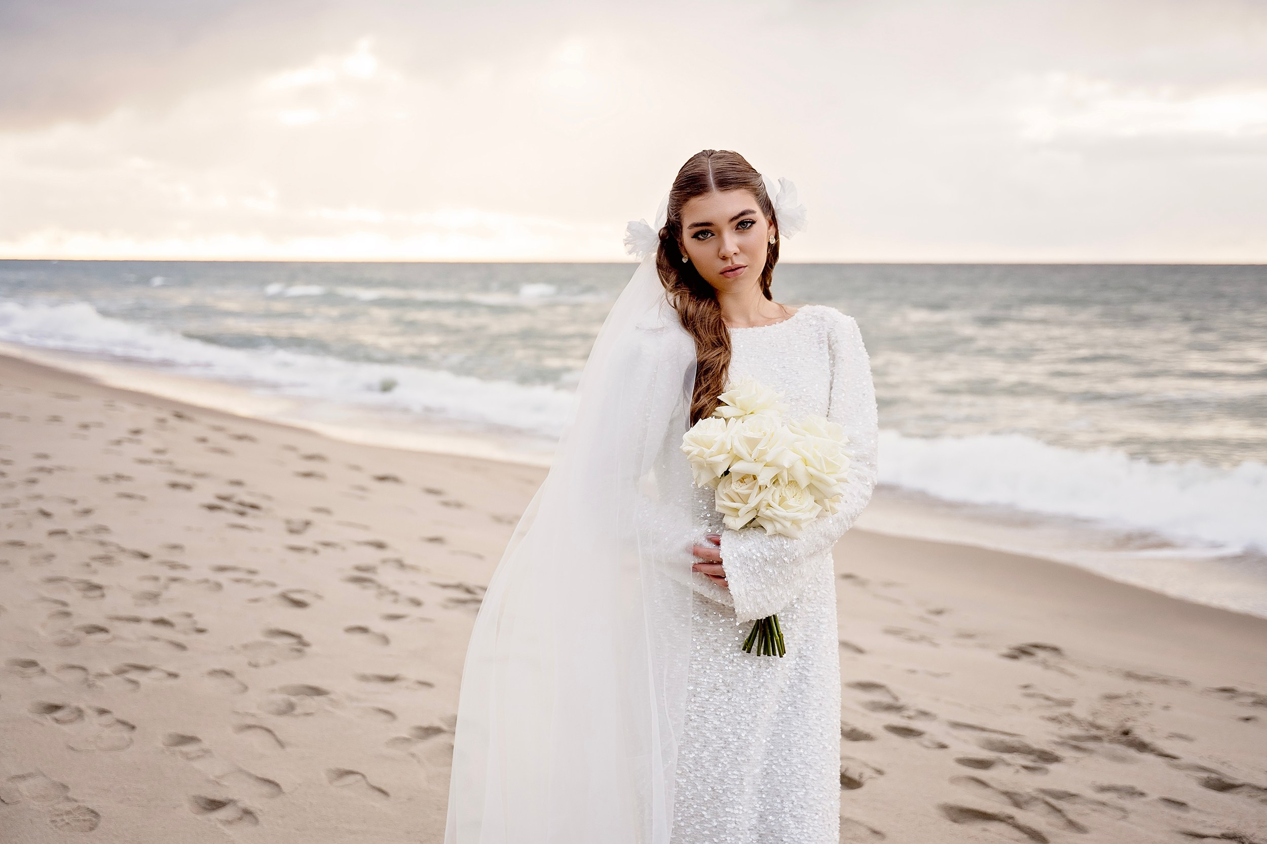 Full-length portrait of a bride in a white gown standing on a sandy beach shore. Destination wedding photographer serving Dublin, Galway, and international clients.