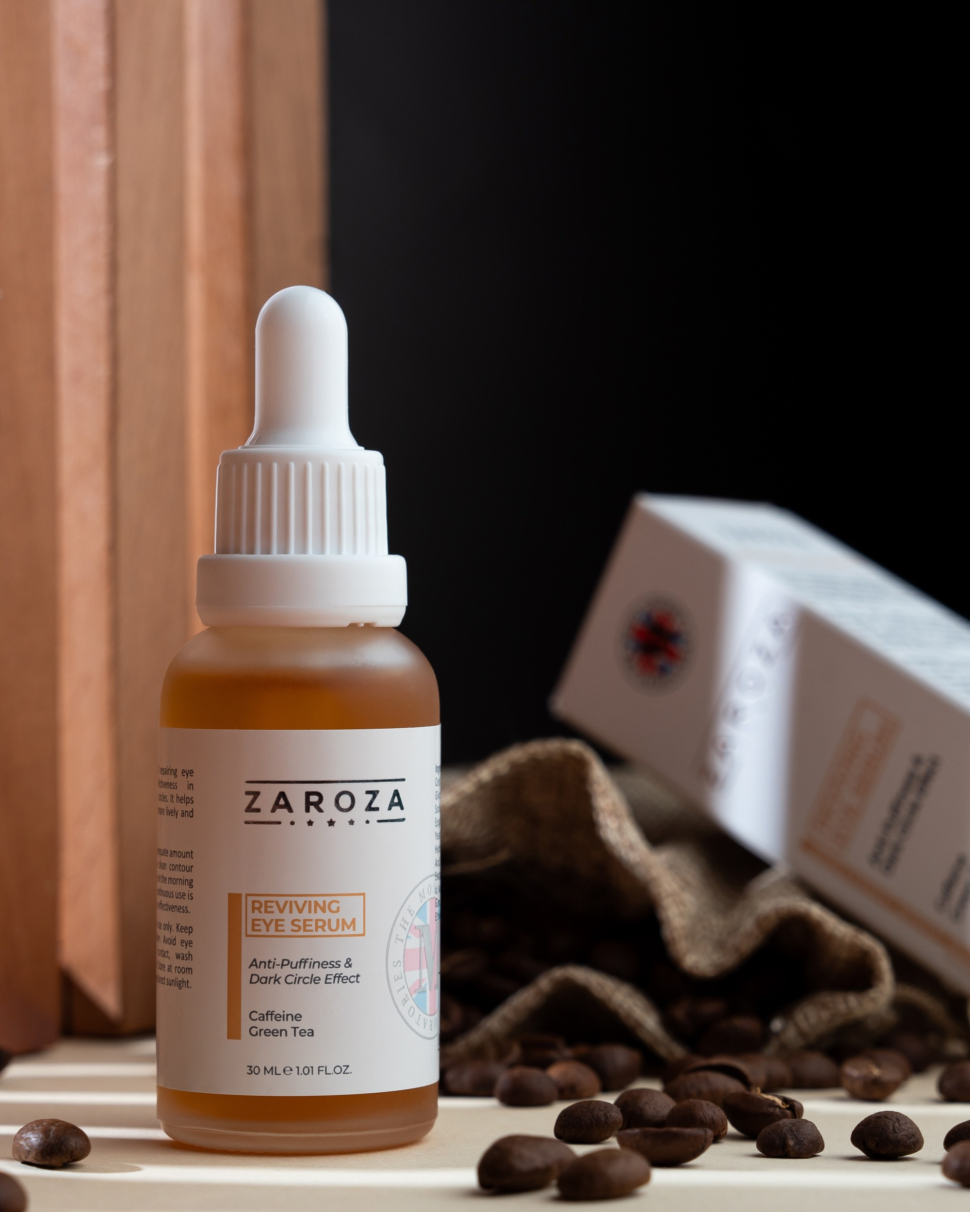 Zaroza Reviving Eye Serum bottle with coffee beans and burlap sack background, wooden and black backdrop product photography.