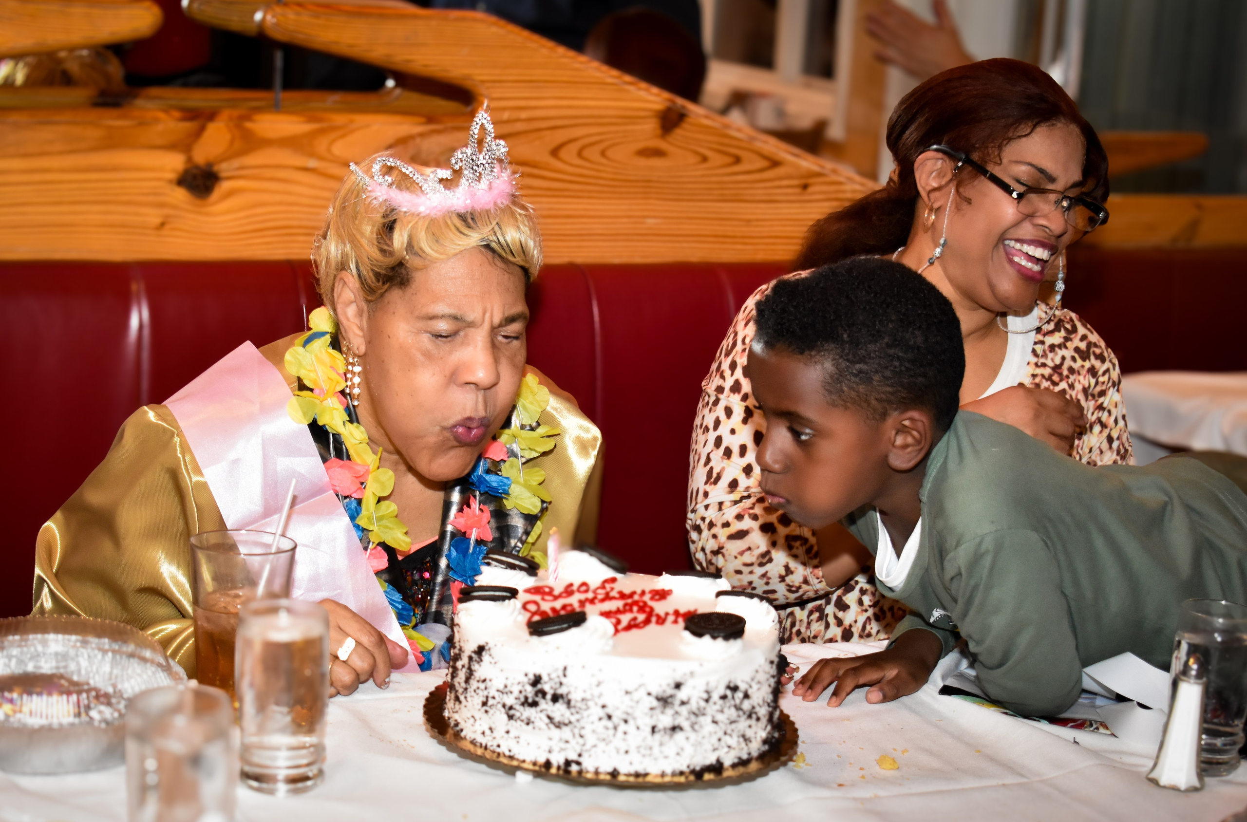 Child wearing a birthday crown at a restaurant table with cake, family birthday celebration photography in NYC.