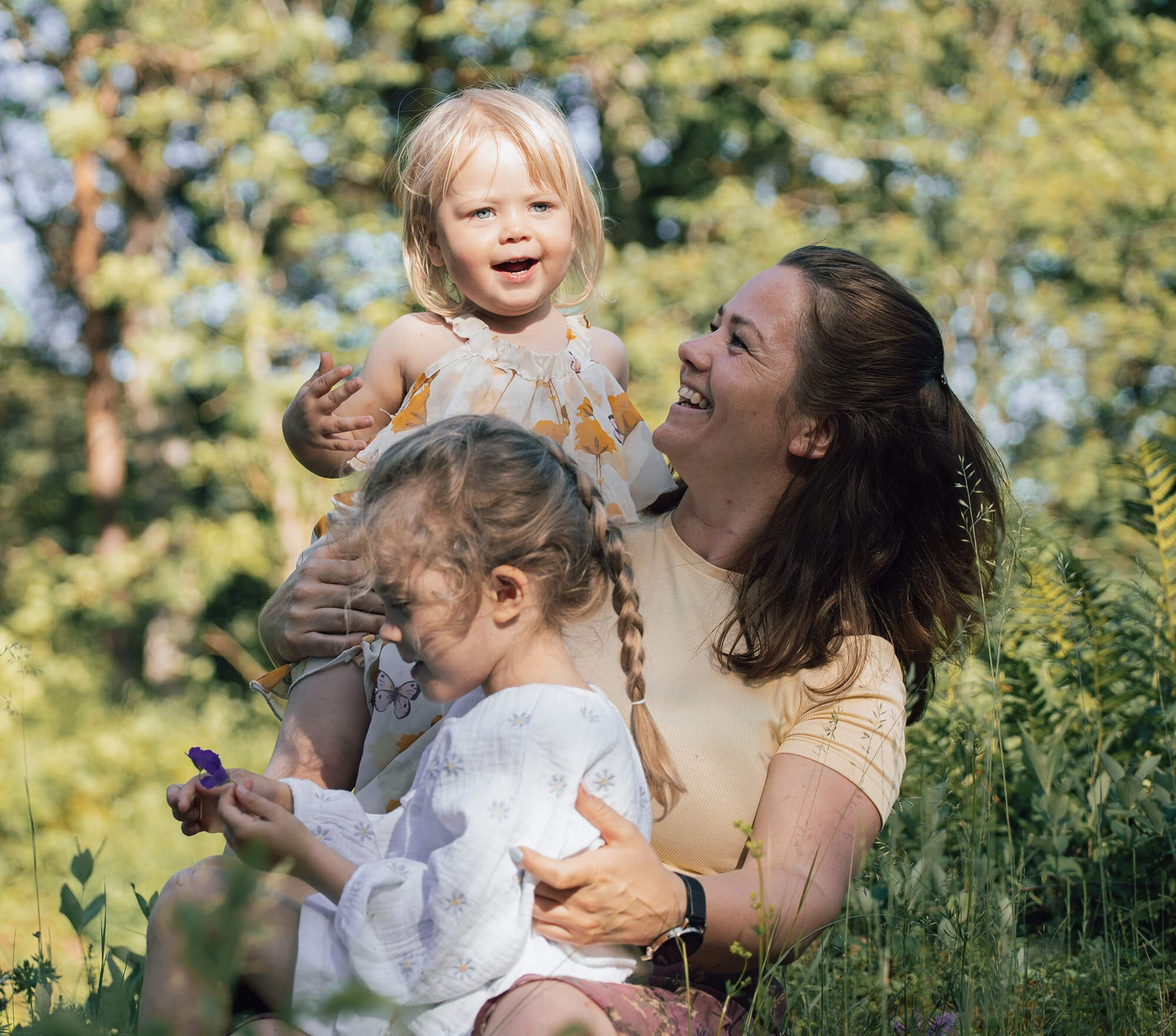 Familie sitter på gresset og ler under fotografering i Porsgrunn