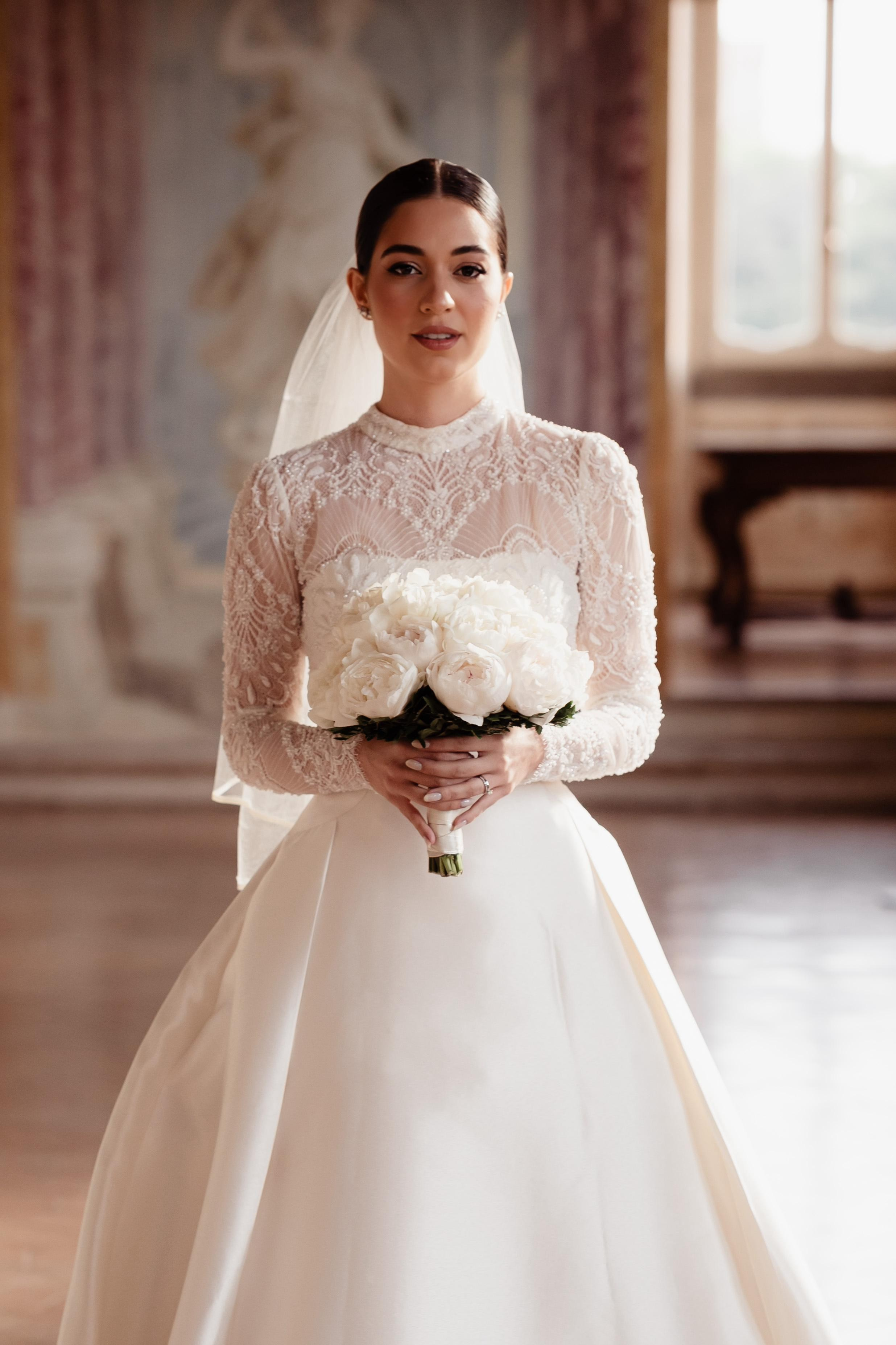 Brazilian bride in a humble wedding dress looking in camera and holding white bouquet