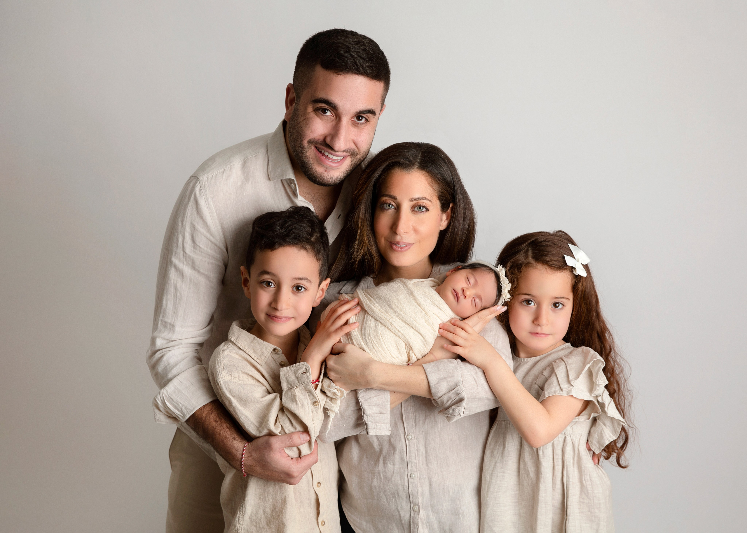 Syskonen håller sin nyfödda bror i famnen, ett fotografi från fototillfället av familjeband och glädje.