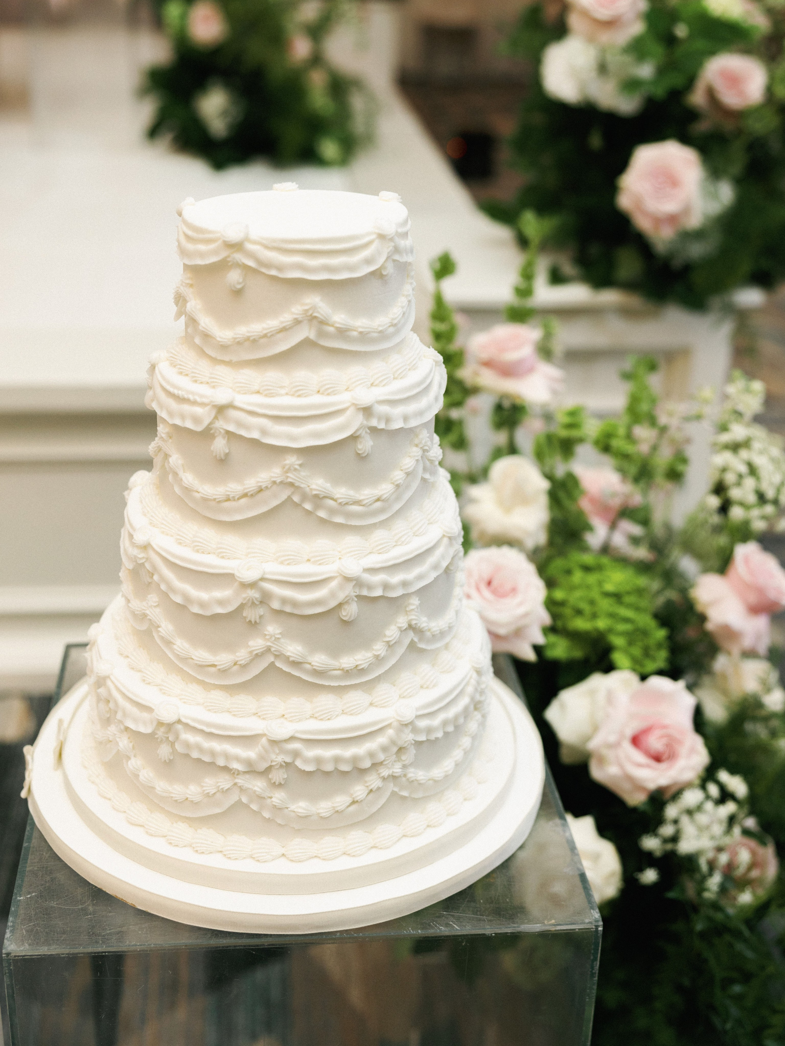 White tiered wedding cake surrounded by flowers