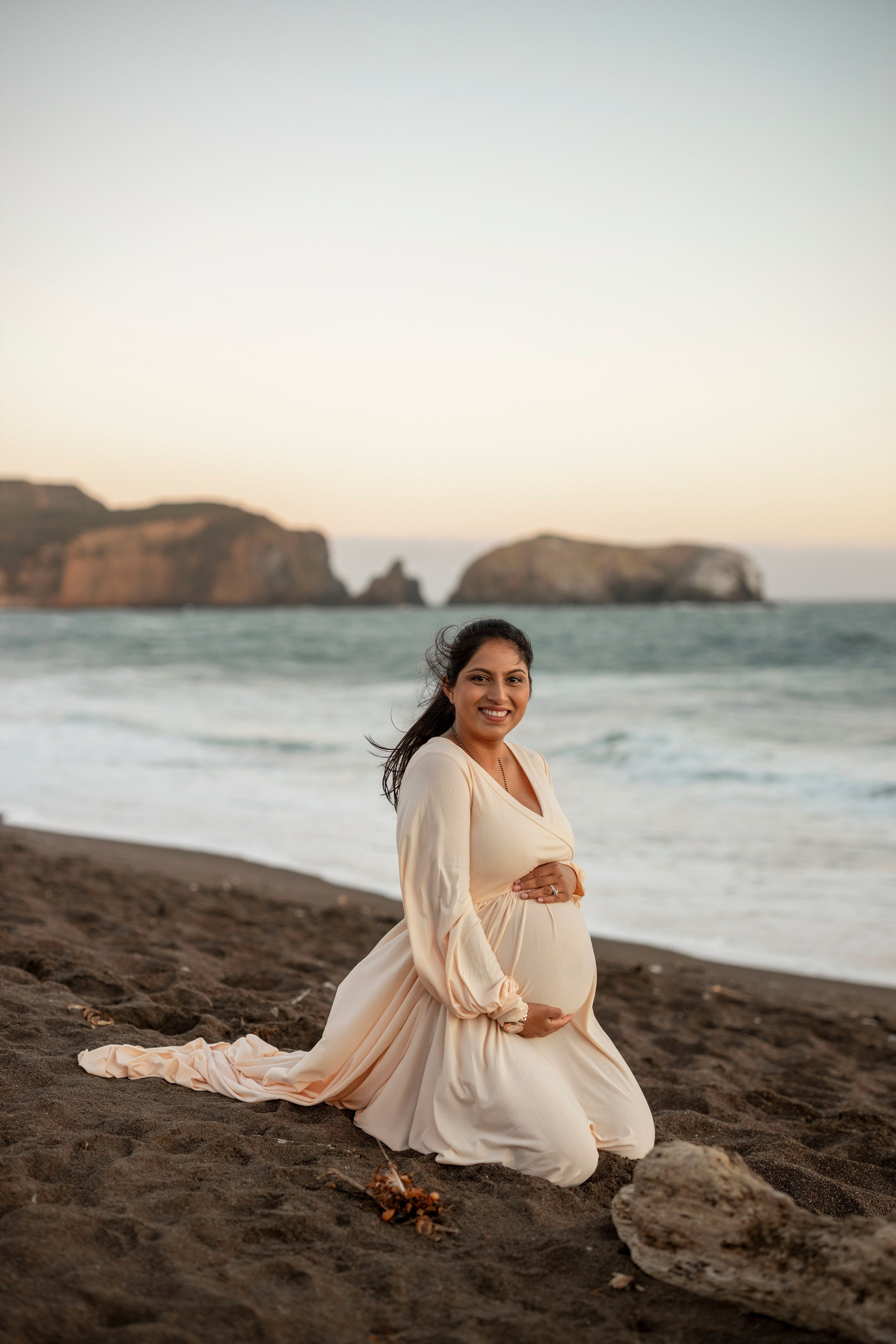 Joyful maternity photoshoot on the beach capturing parenthood moments