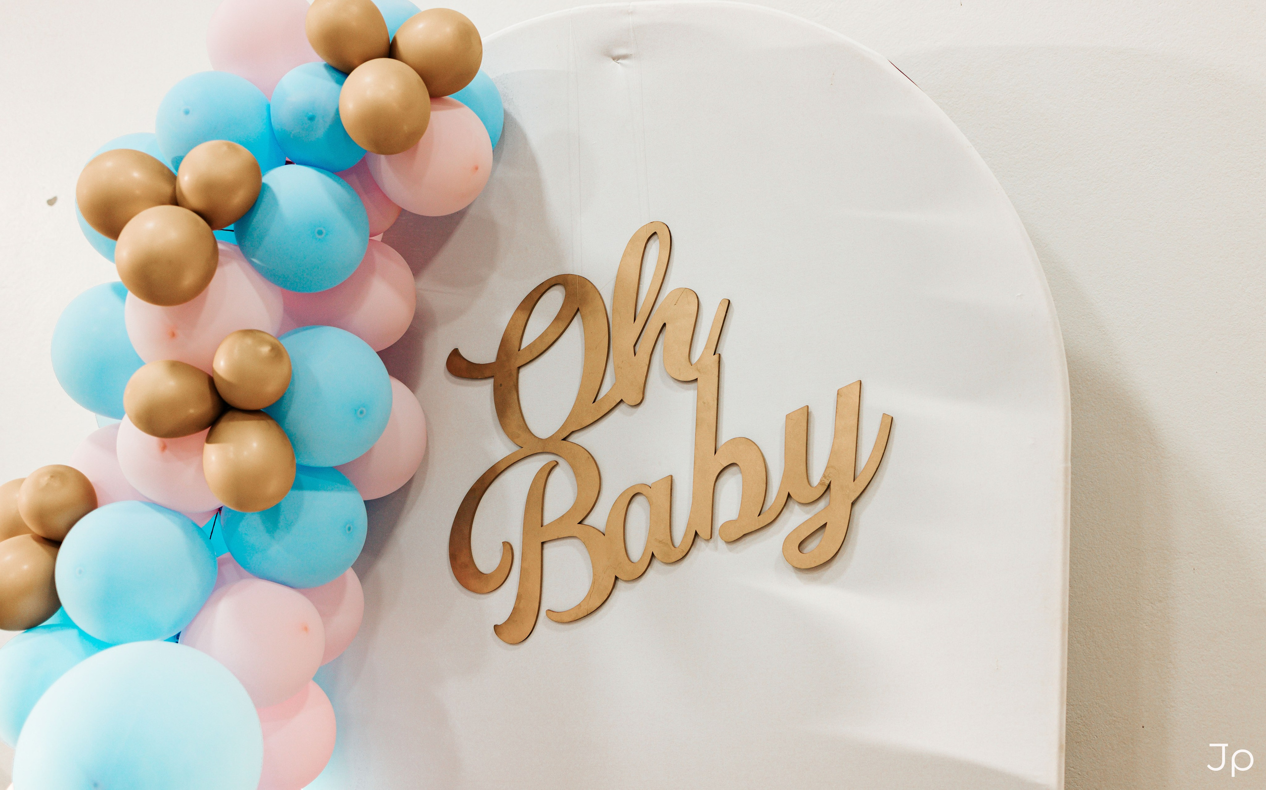 Detalhe do letreiro dourado “Oh Baby” com balões coloridos