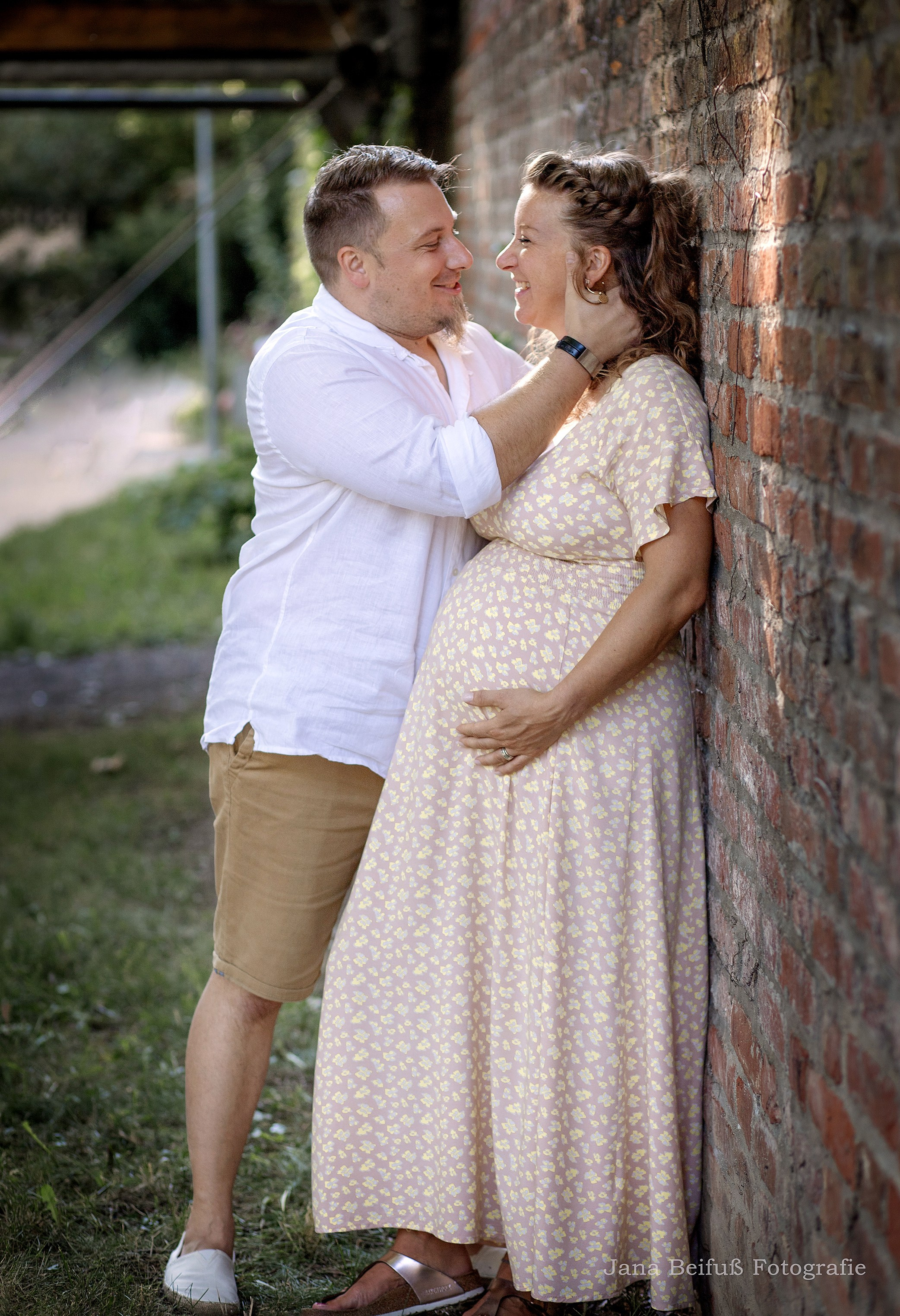 glückliche werdende Eltern küssen sich bei einer Backsteinwand in Weißenhorn - Schwangerschaftsfotografie Weißenhorn bei Ulm