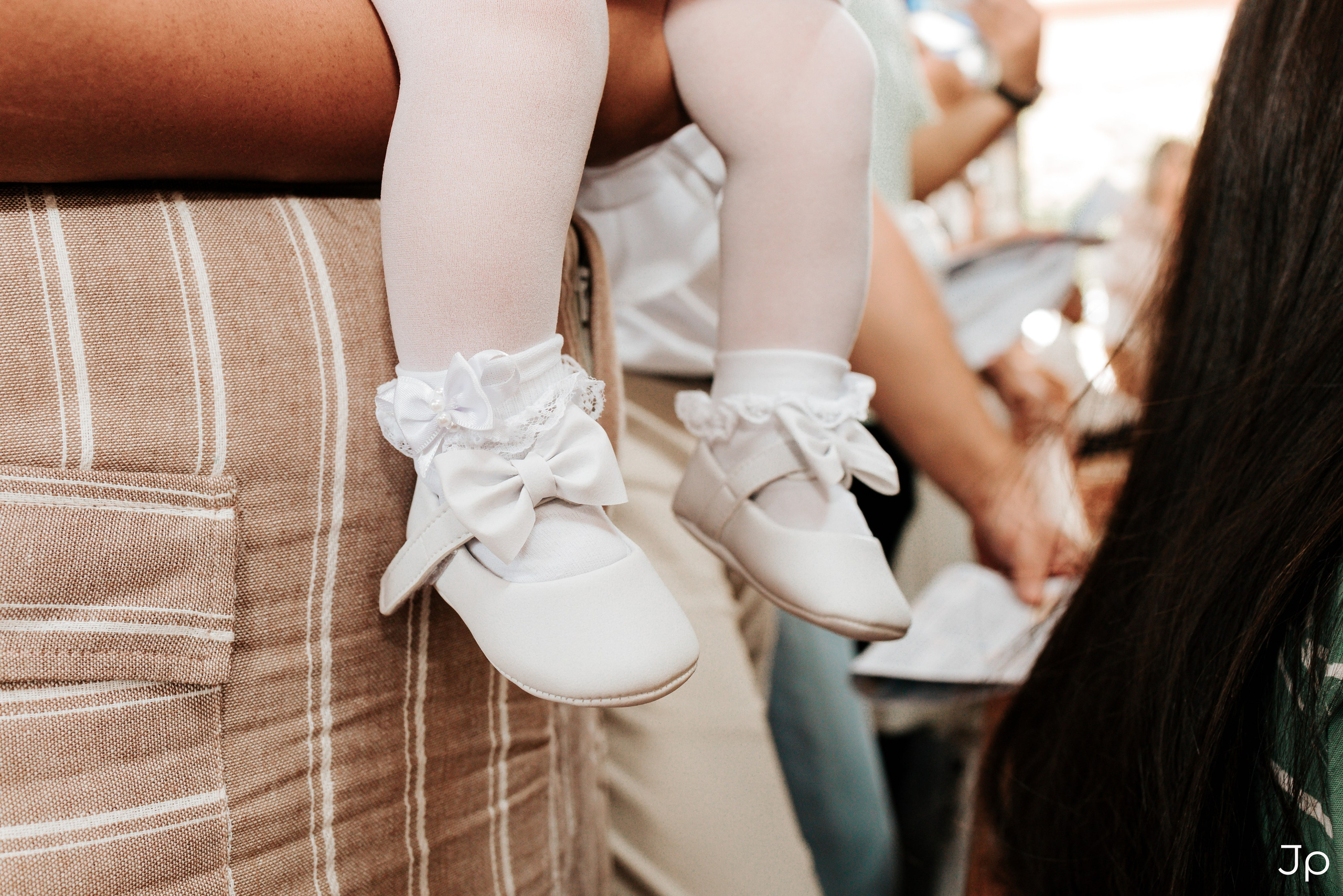 Detalhe dos pezinhos do bebê com sapatinhos brancos.
