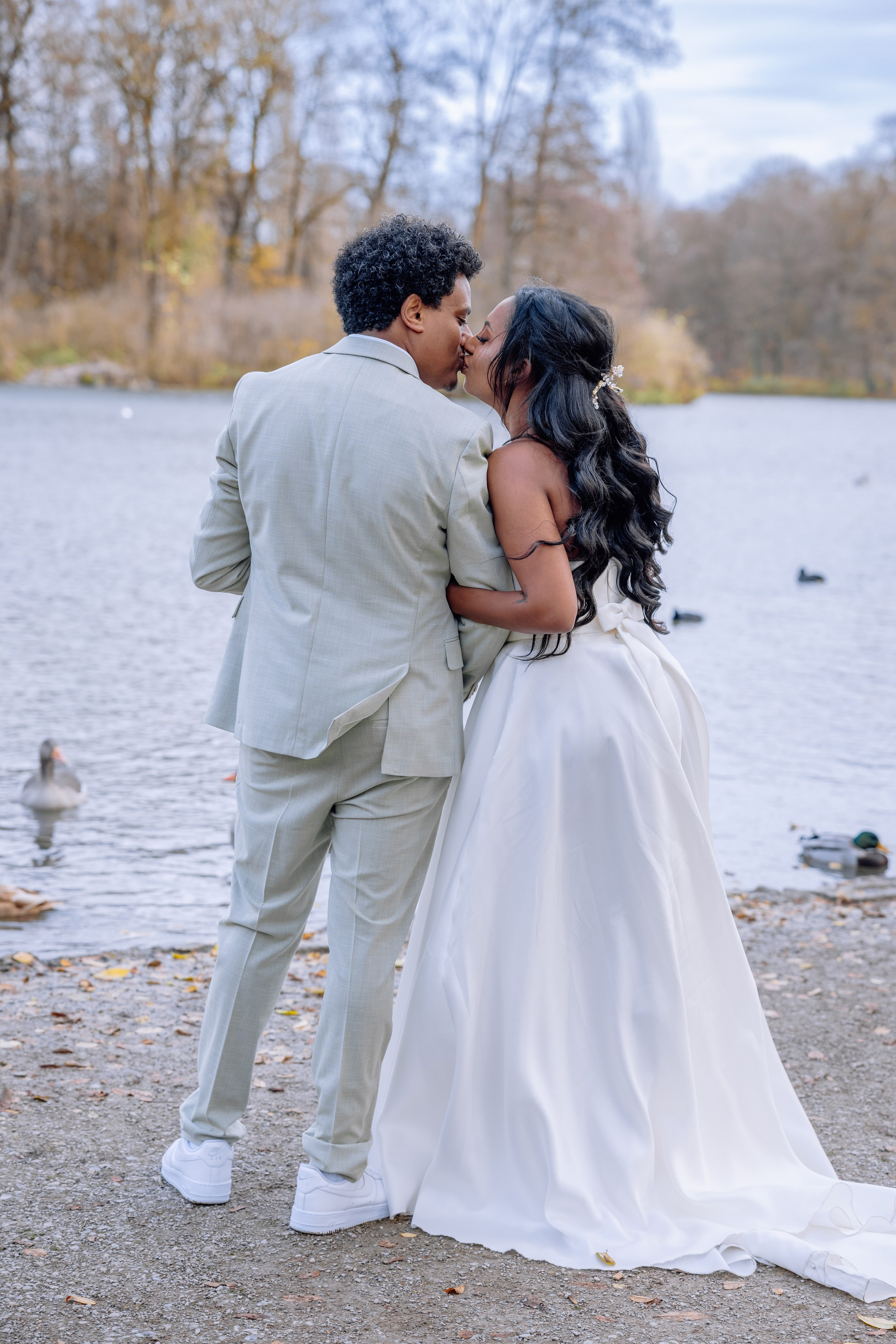 Fotografiert von hinten – Brautpaar beobachtet Enten im Teich neben Mandlstraße 14