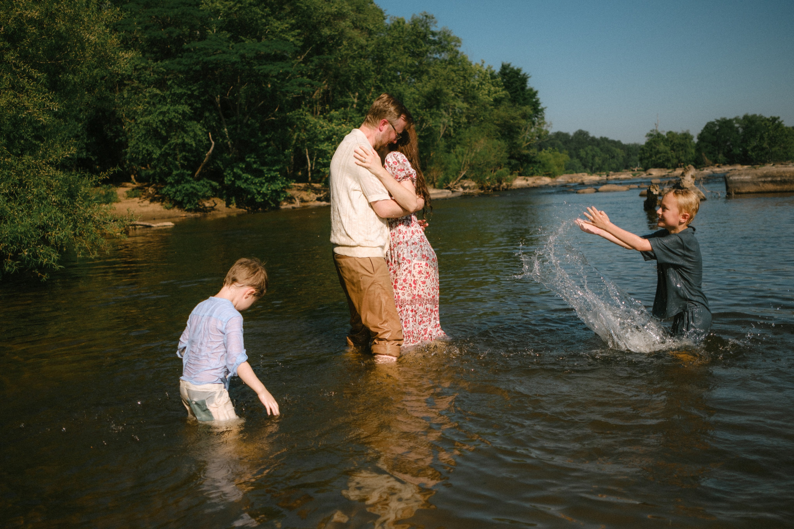 Kids splashing their parents during an adventurous outdoor family photography session at Pony Pasture in Richmond, VA