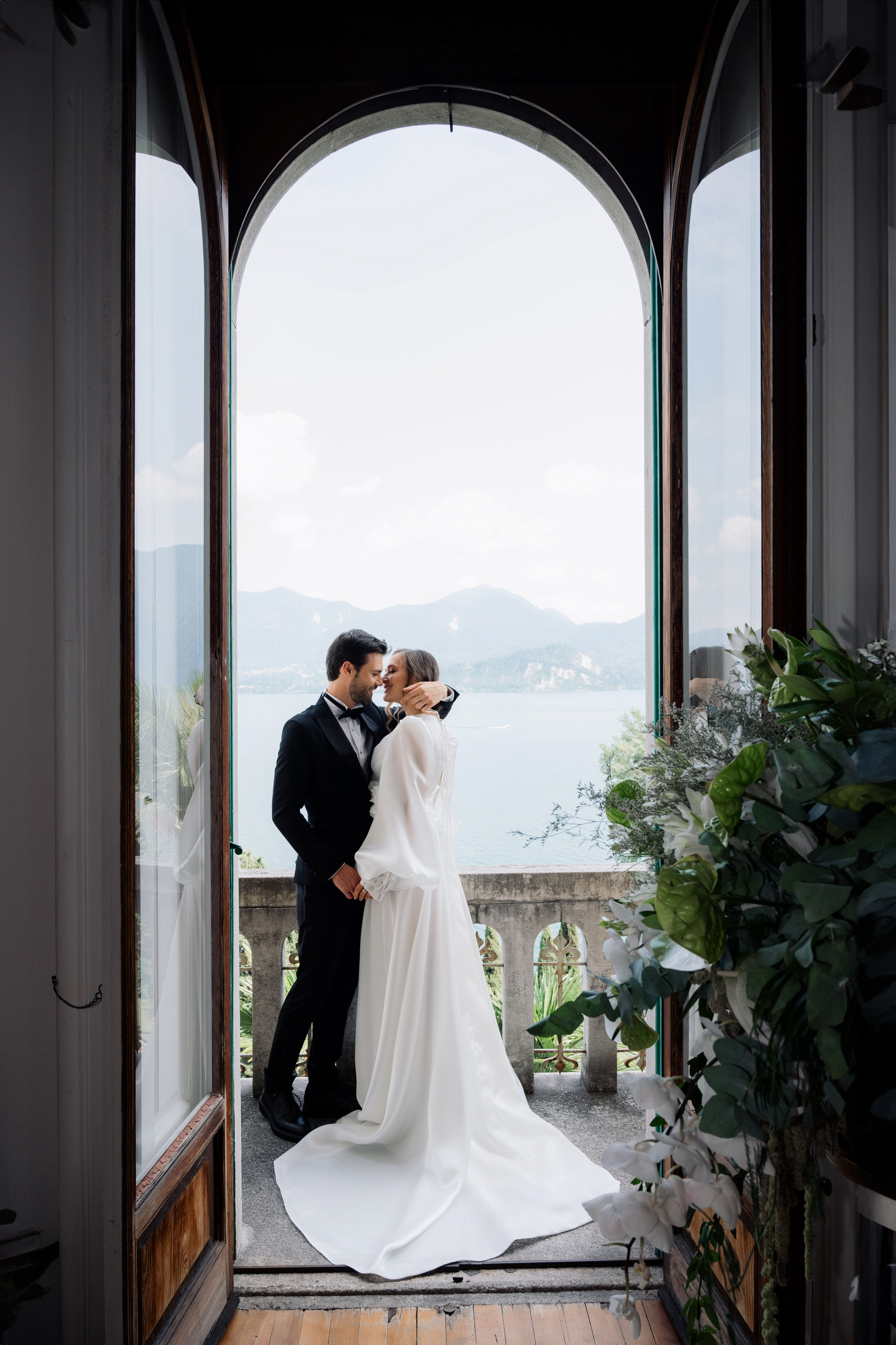 a bride and groom kissing in front of a window