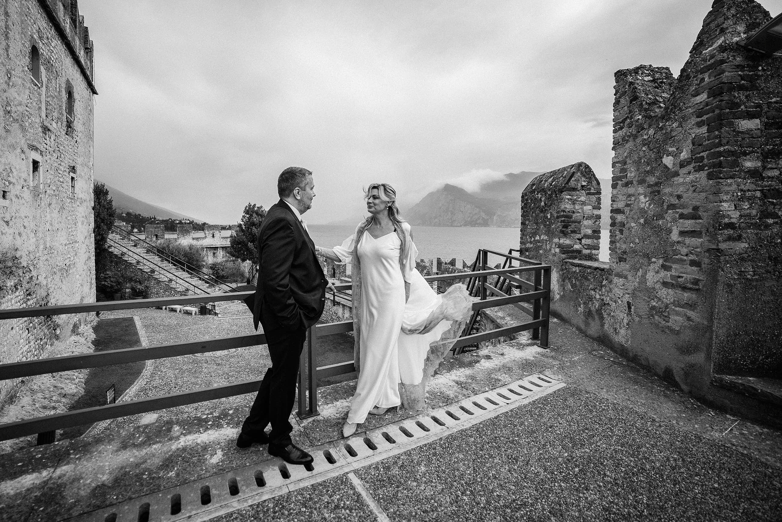  La Sposa con bellissimo vestito e lo sposo in Castello Scaligero in Malcesine durante la sessione fotografica.Fotografo di Matrimonio sul lago di Garda.