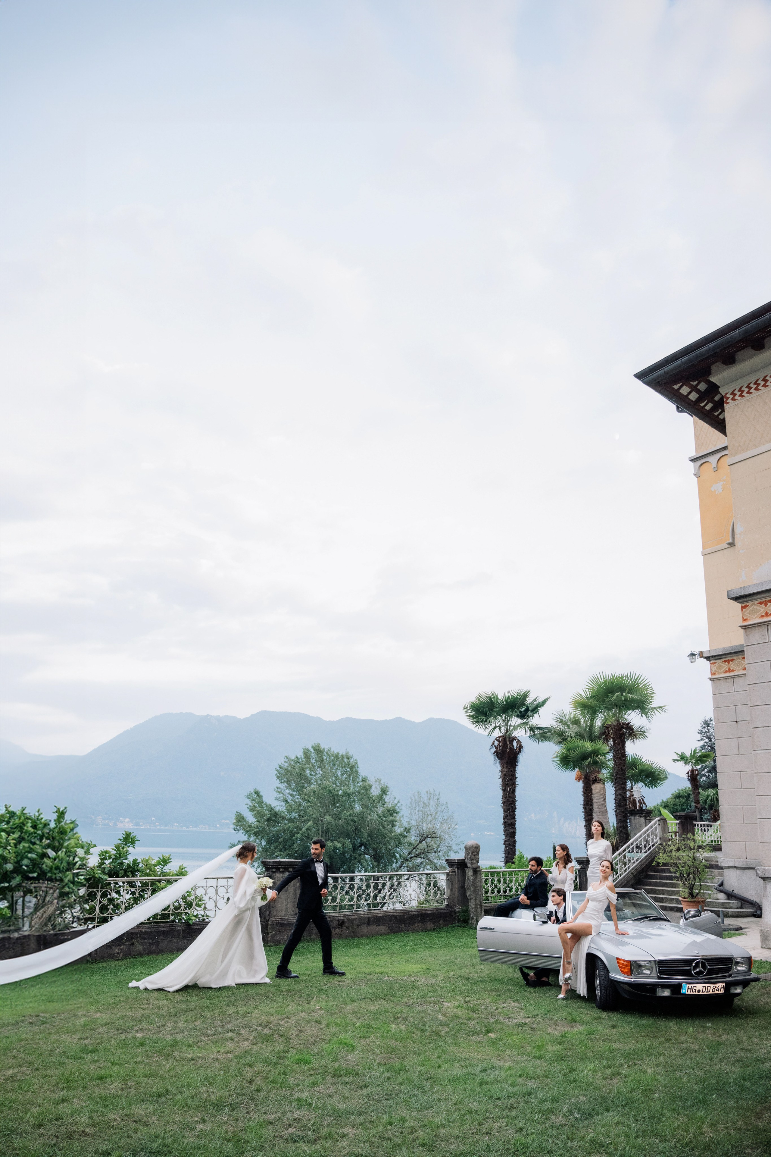 a bride and groom standing in front of a car