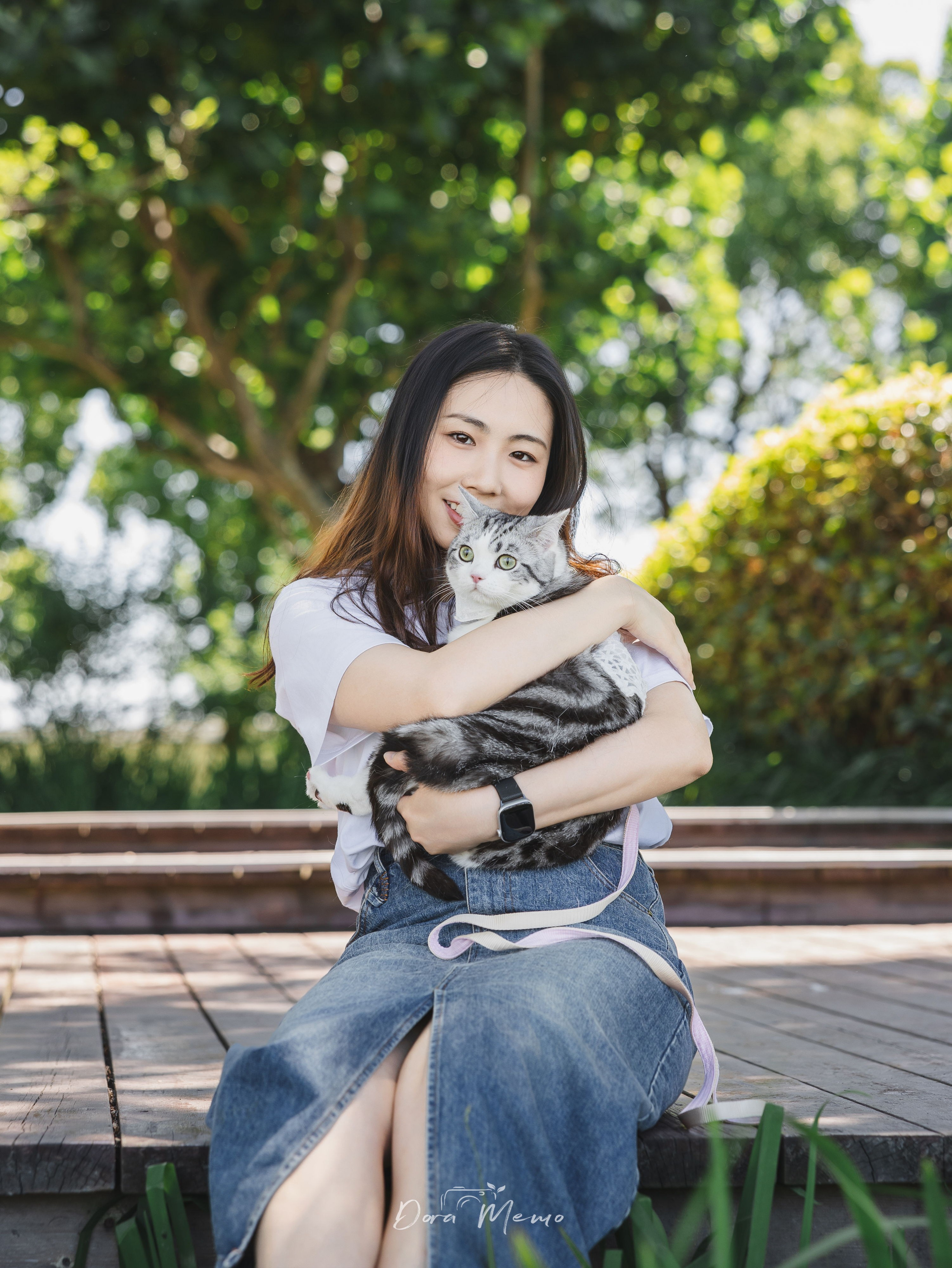 Woman embracing her cat on a wooden bench, warm afternoon light