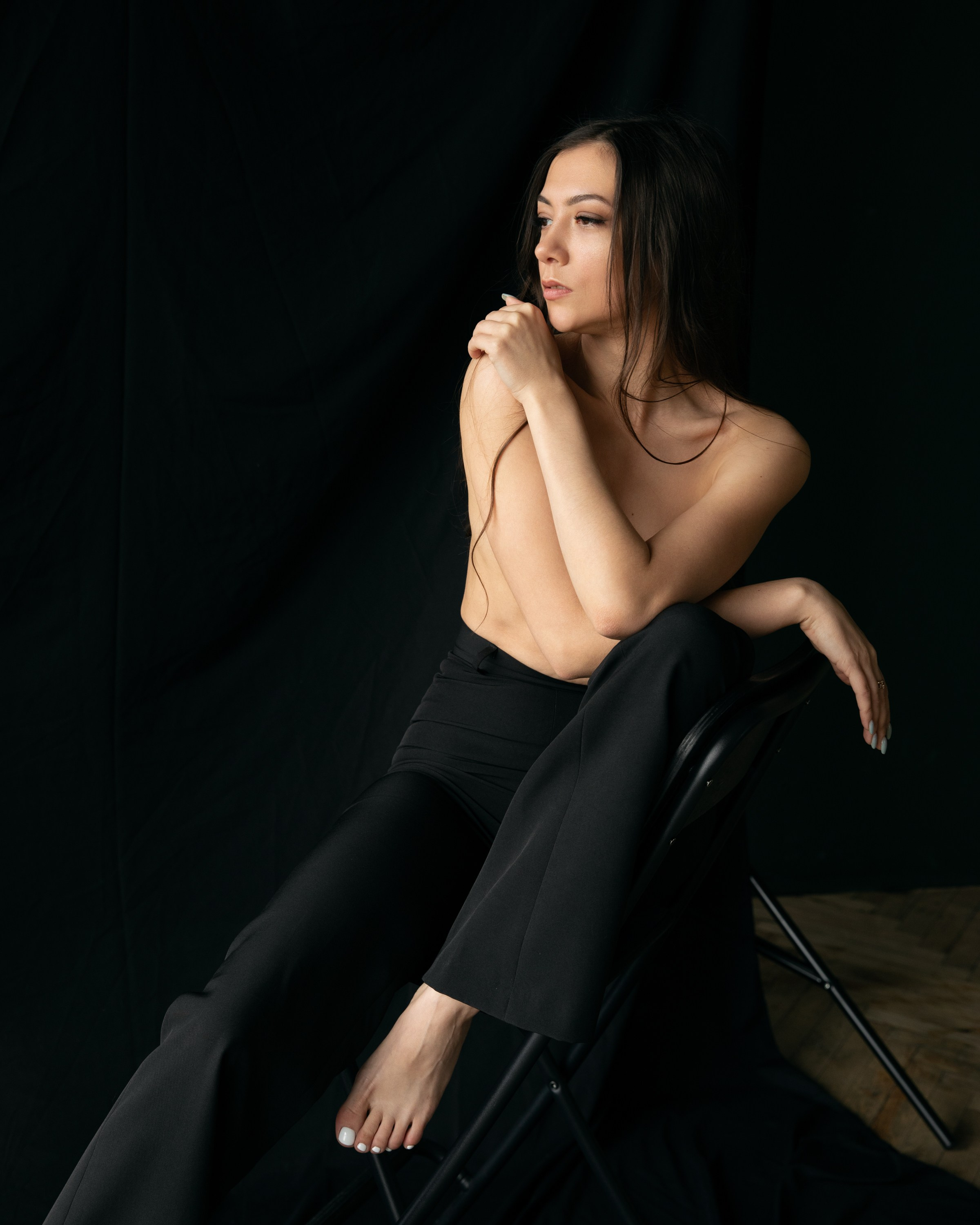 Minimalistisches Porträt einer Frau auf schwarzem Stuhl