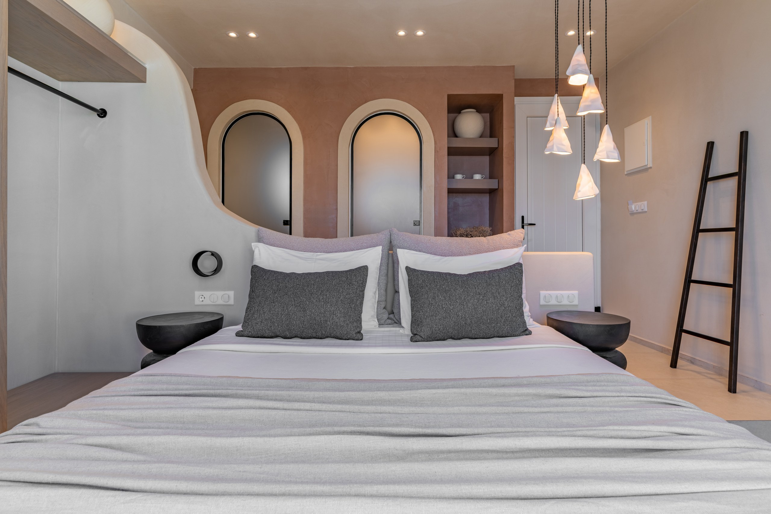 Close-up on the inviting, plush white bedding and charcoal pillows, highlighting the serene aesthetic of Fotis Bakas' design. Boutique hotel photography in Astypalaia.