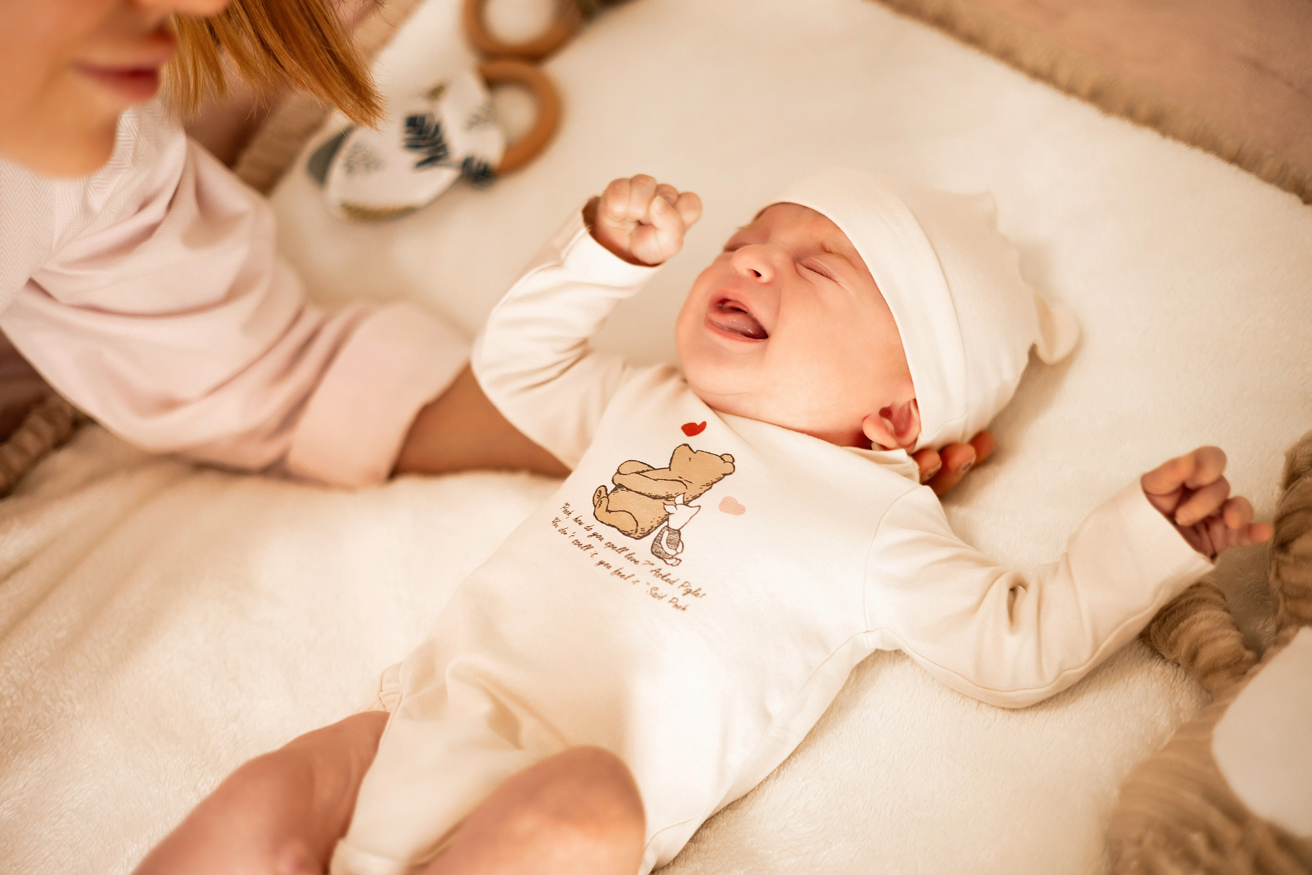 Newborn surrounded by soft toys on the bed