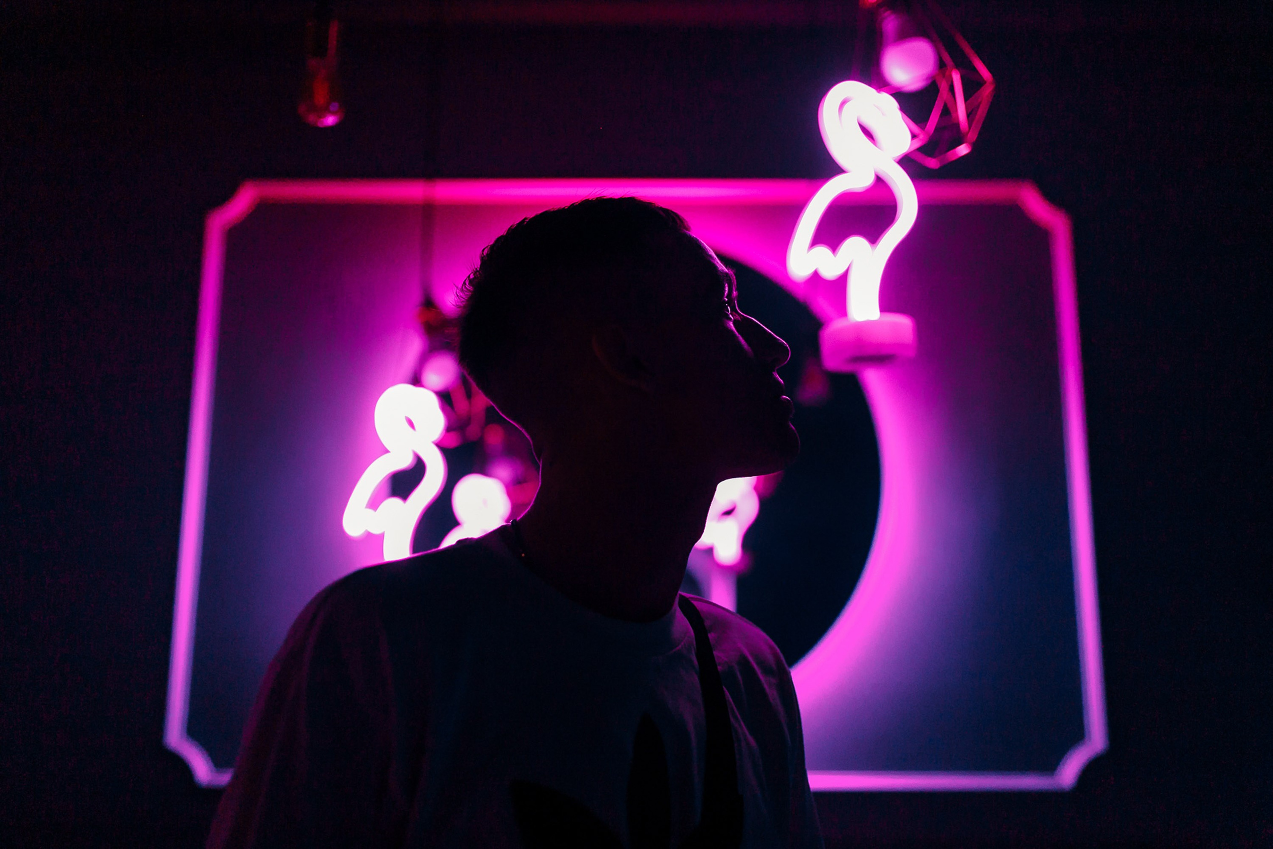 Person in black hat with neon purple background