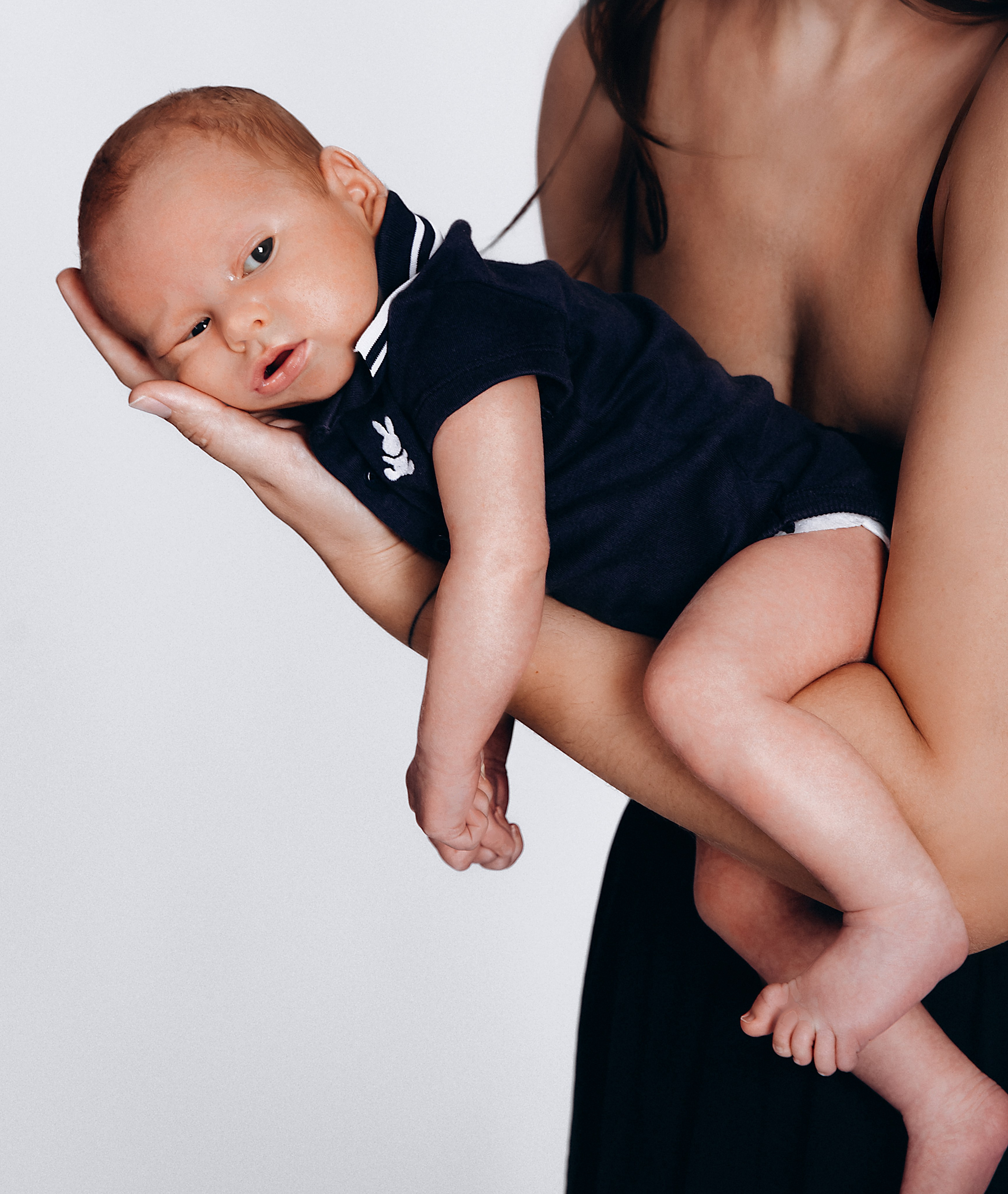Sesión familiar de recién nacido en estudio en Valencia, España — retrato íntimo y artístico de un bebé descansando en brazos de su madre, ideal para familias que buscan fotografía tierna y atemporal en Valencia y España.