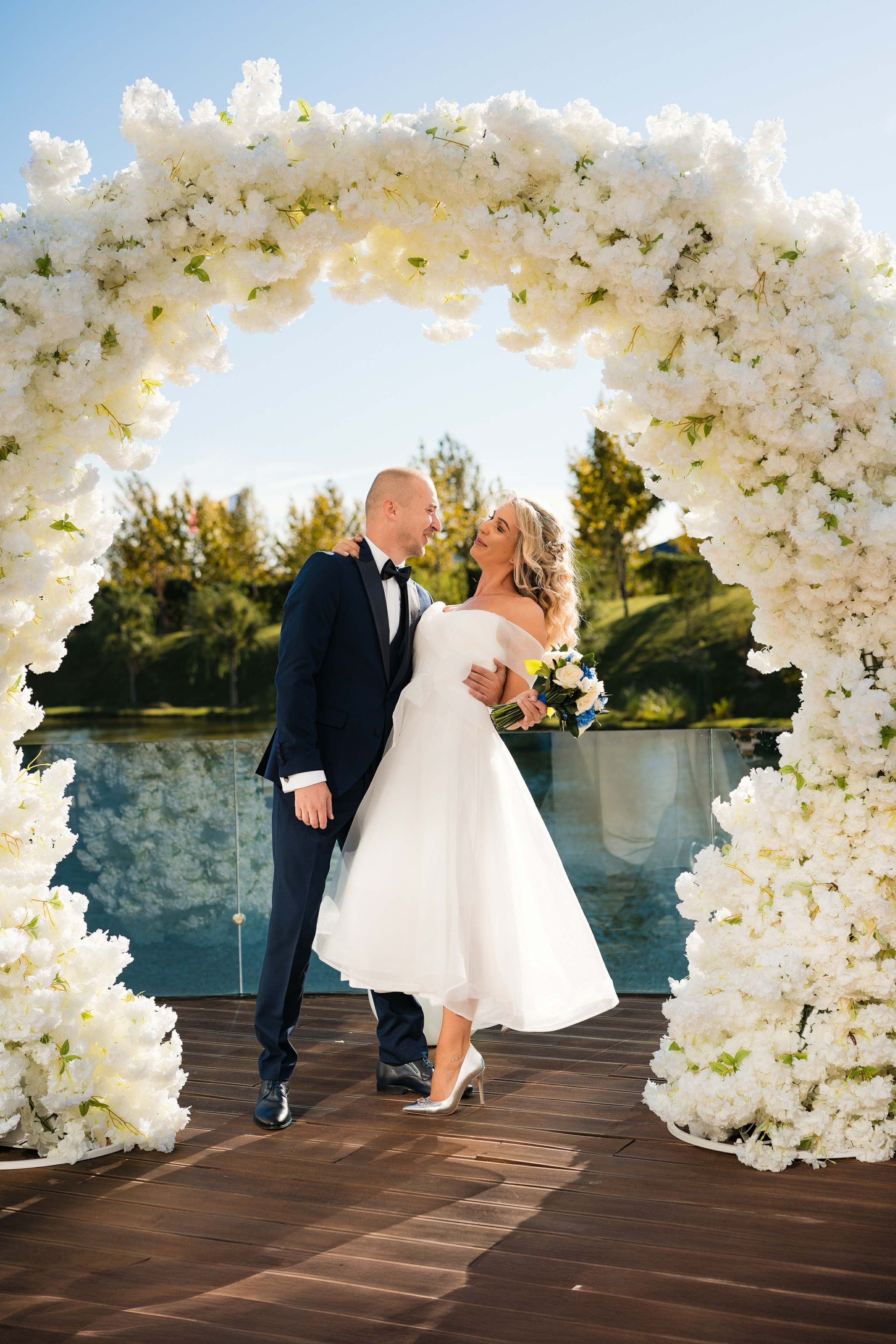 Mireasa râzând în brațele mirelui, într-un peisaj de poveste