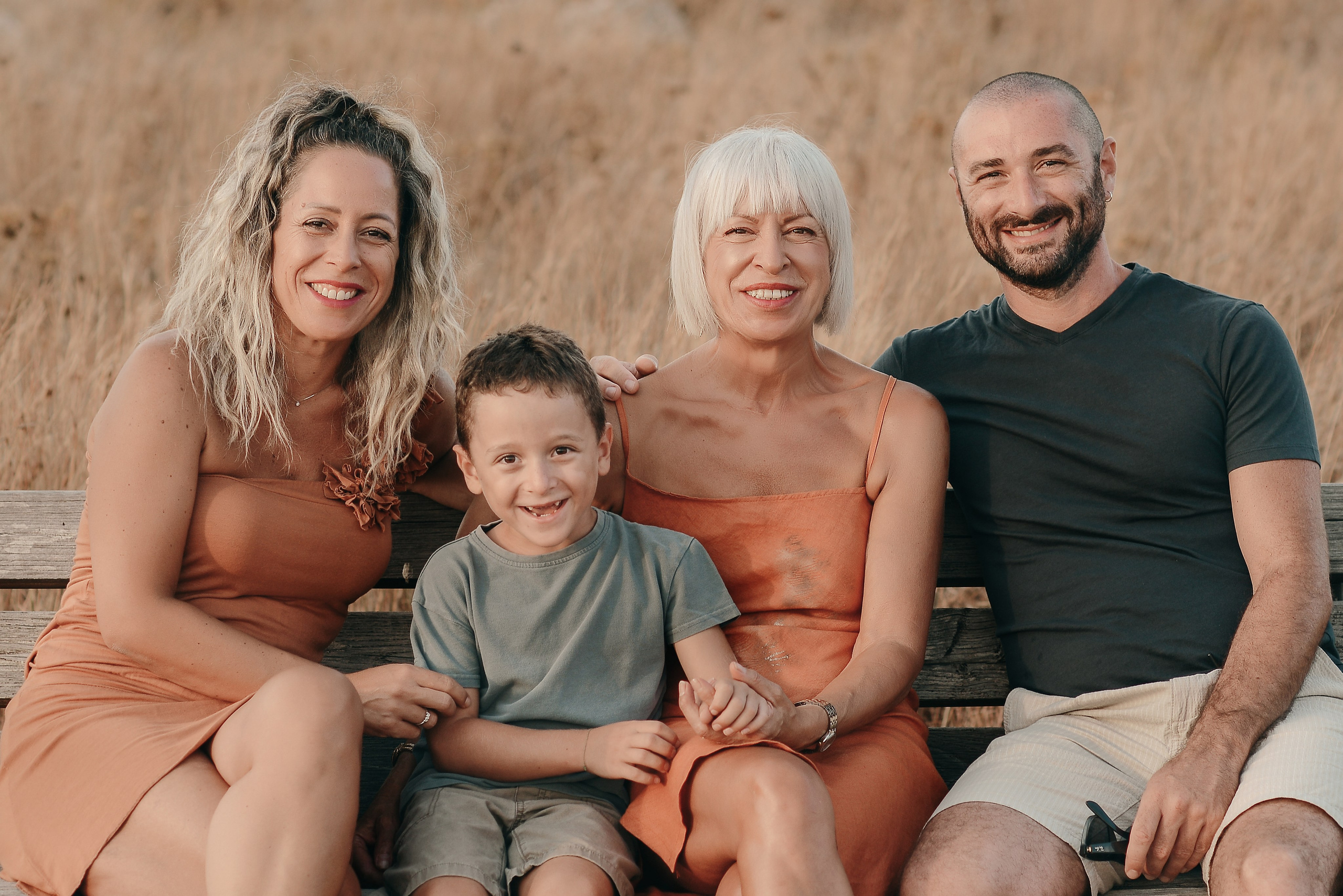 Family of four enjoying a golden hour moment in the countryside of Puglia — warm smiles and a relaxed summer evening atmosphere.
